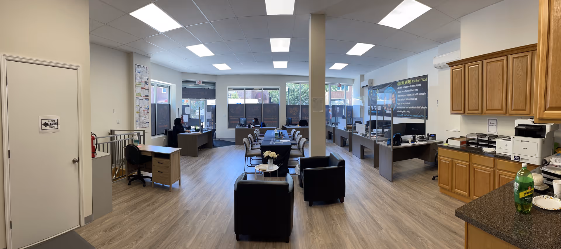 Open, well-lit reception/workspace with desks, cubicles, and a kitchenette at Marks Home Care.