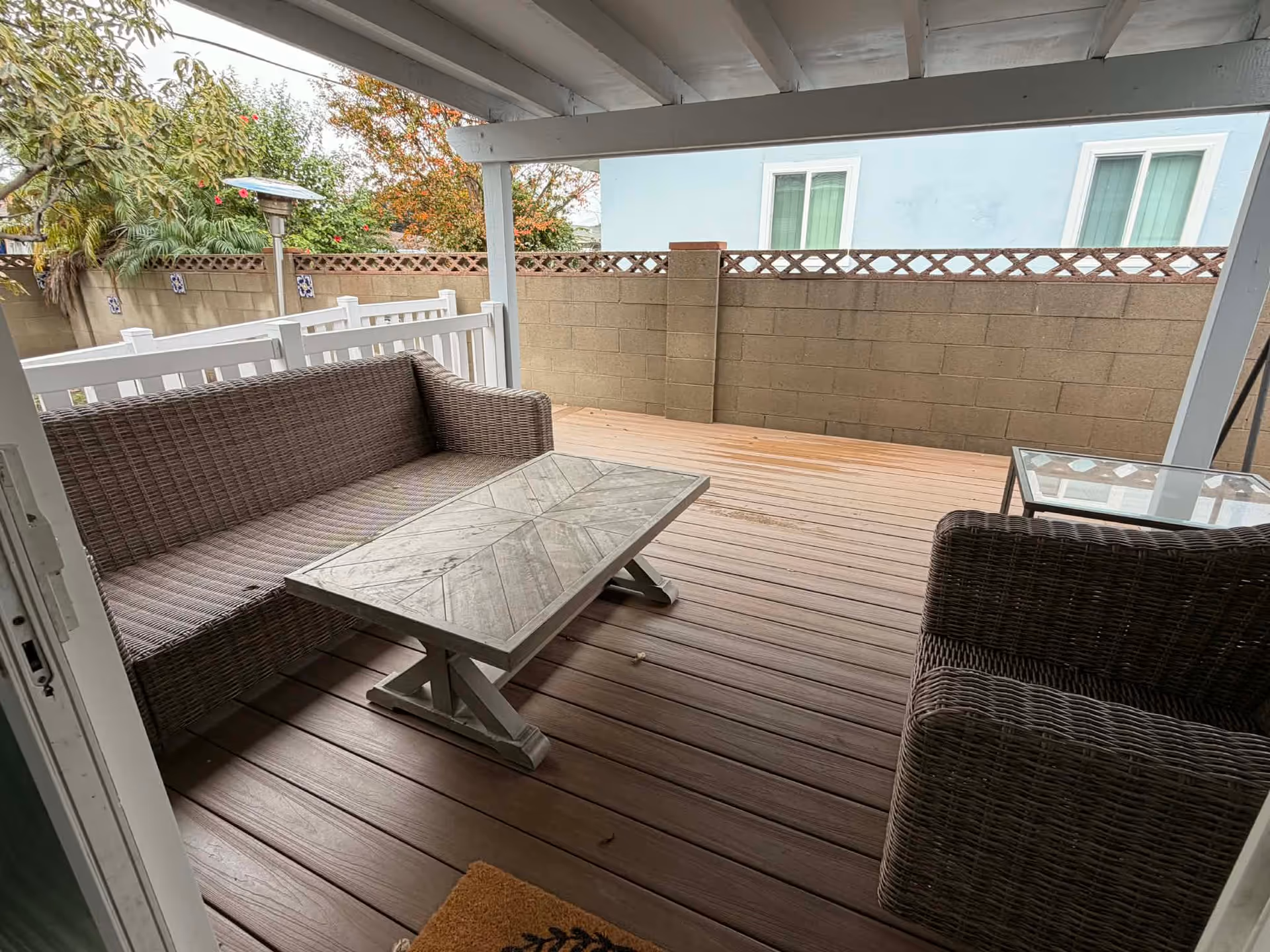Covered outdoor patio with wicker furniture and a glass coffee table.