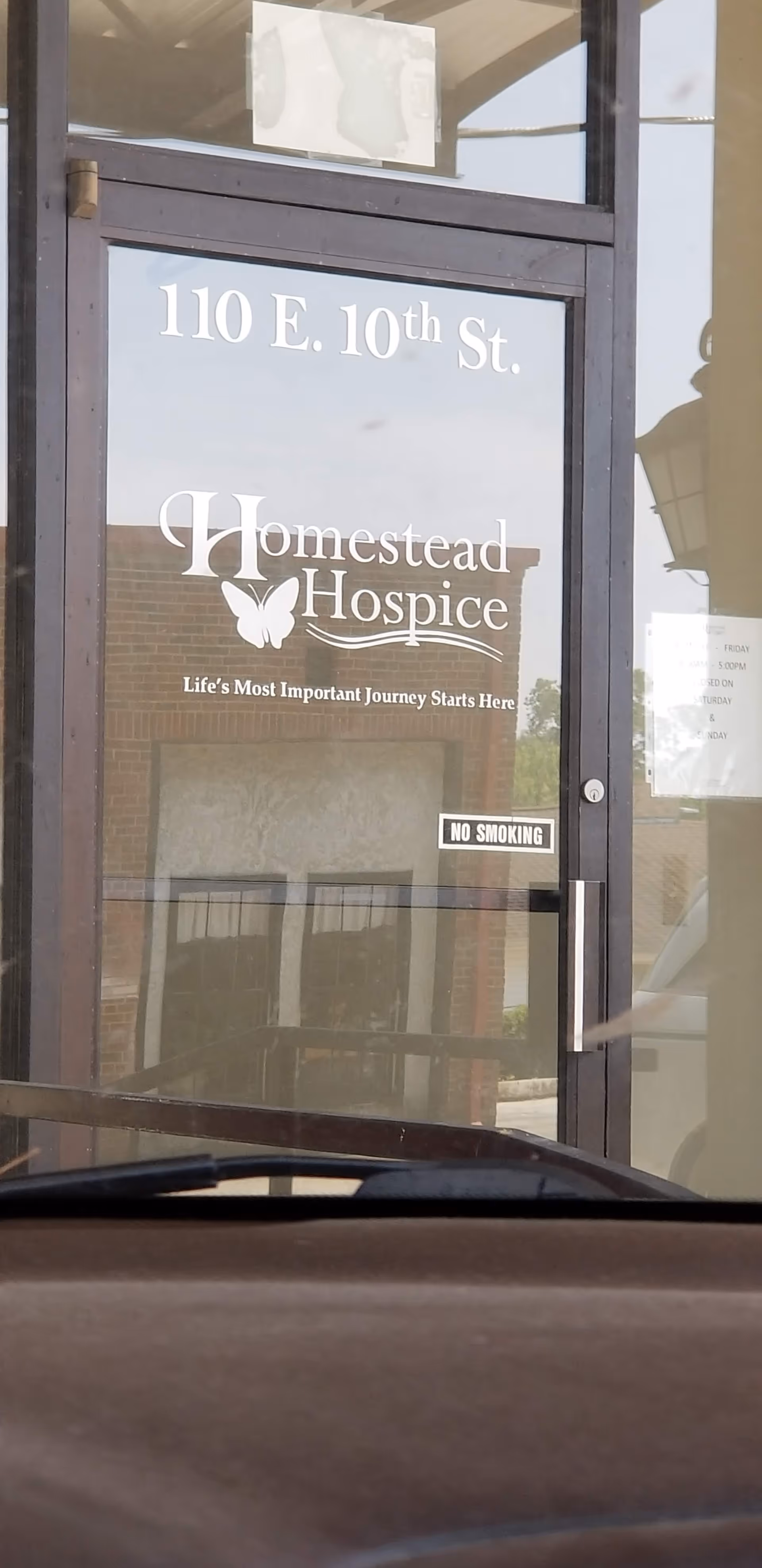 Front glass door displaying Homestead Hospice sign and address 110 E. 10th St.