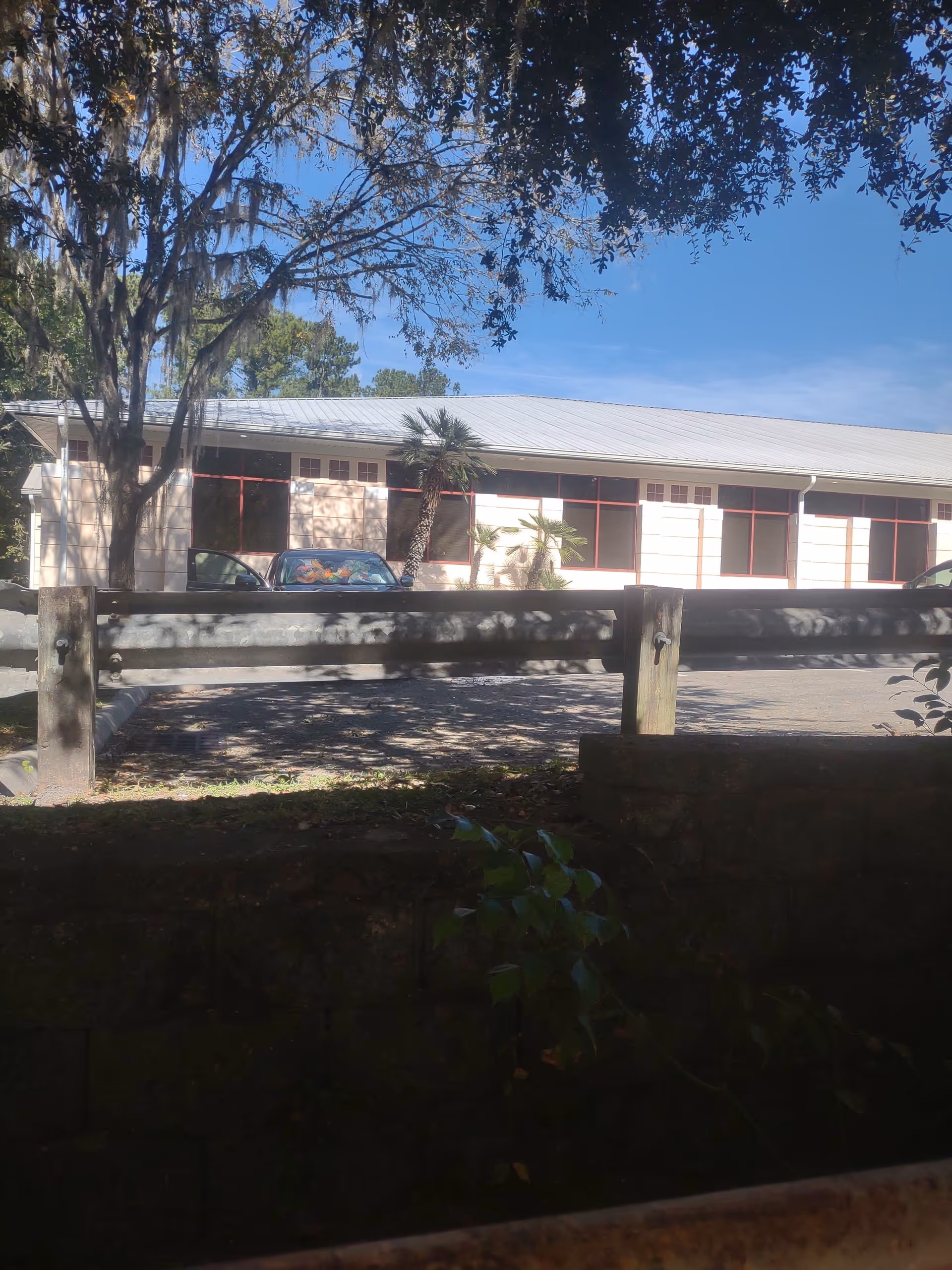 Exterior view of a UF Health Shands HomeCare building with a fence and trees.