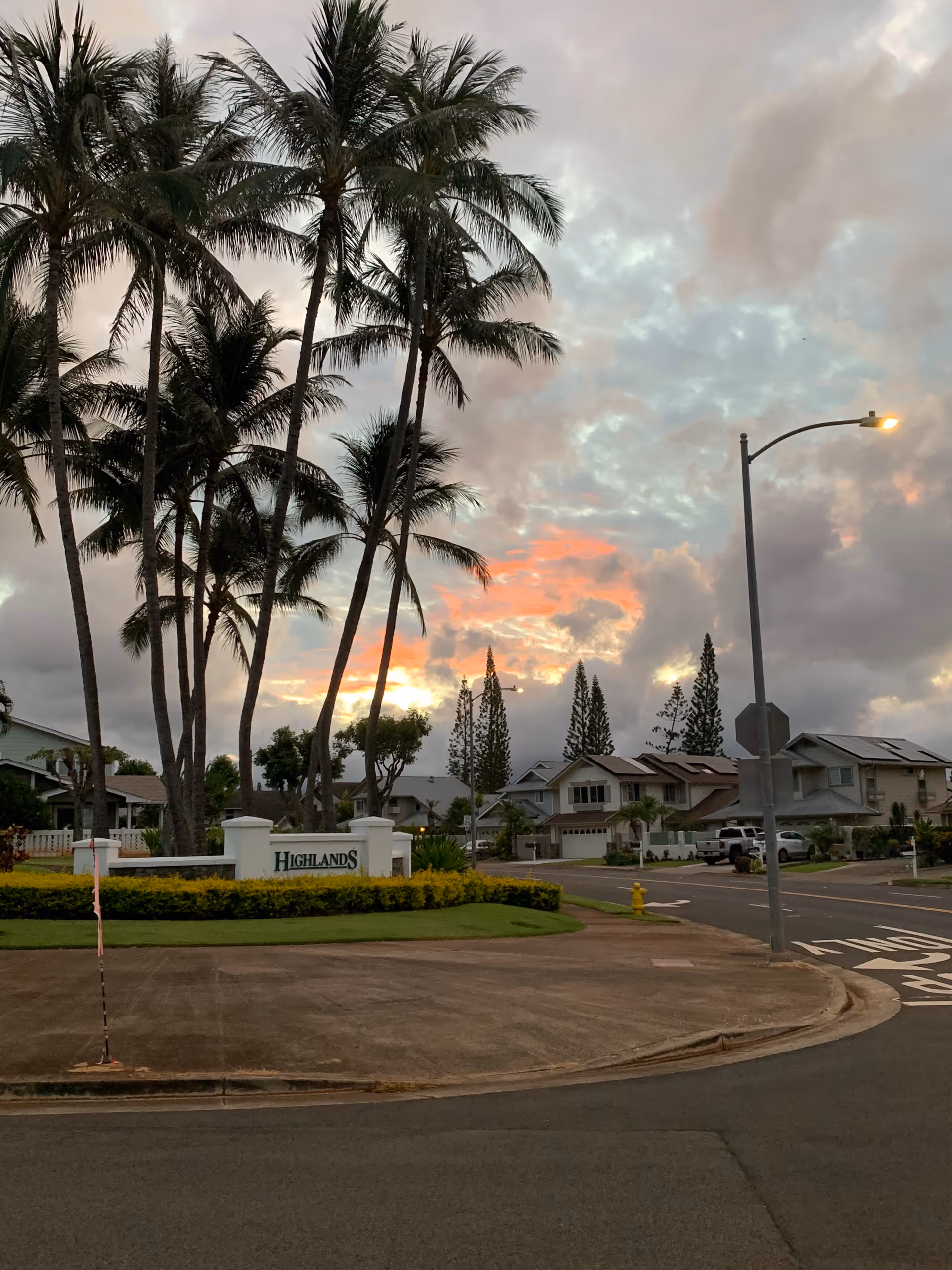 Sunset over a senior living community entrance with palm trees and Highlands sign