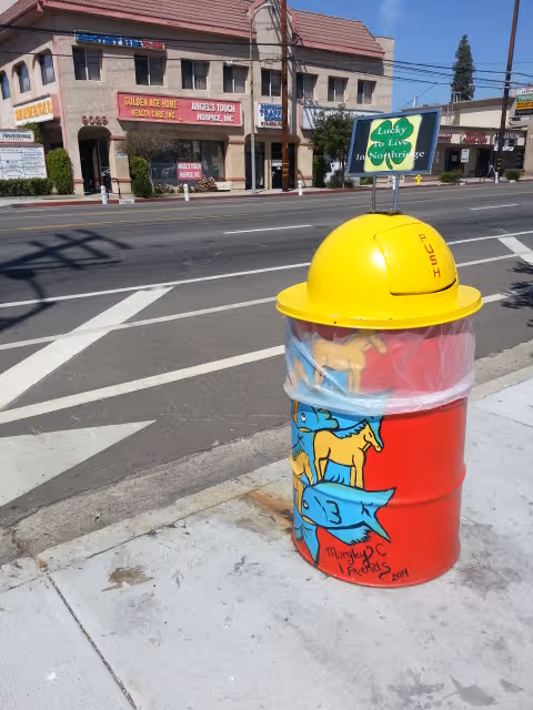 Street scene with graffiti trash can and building signage for Golden Age Home Health Care Inc.