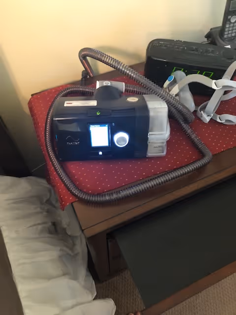 Medical equipment and tubing sit on a red-dotted bedside table in a bedroom.