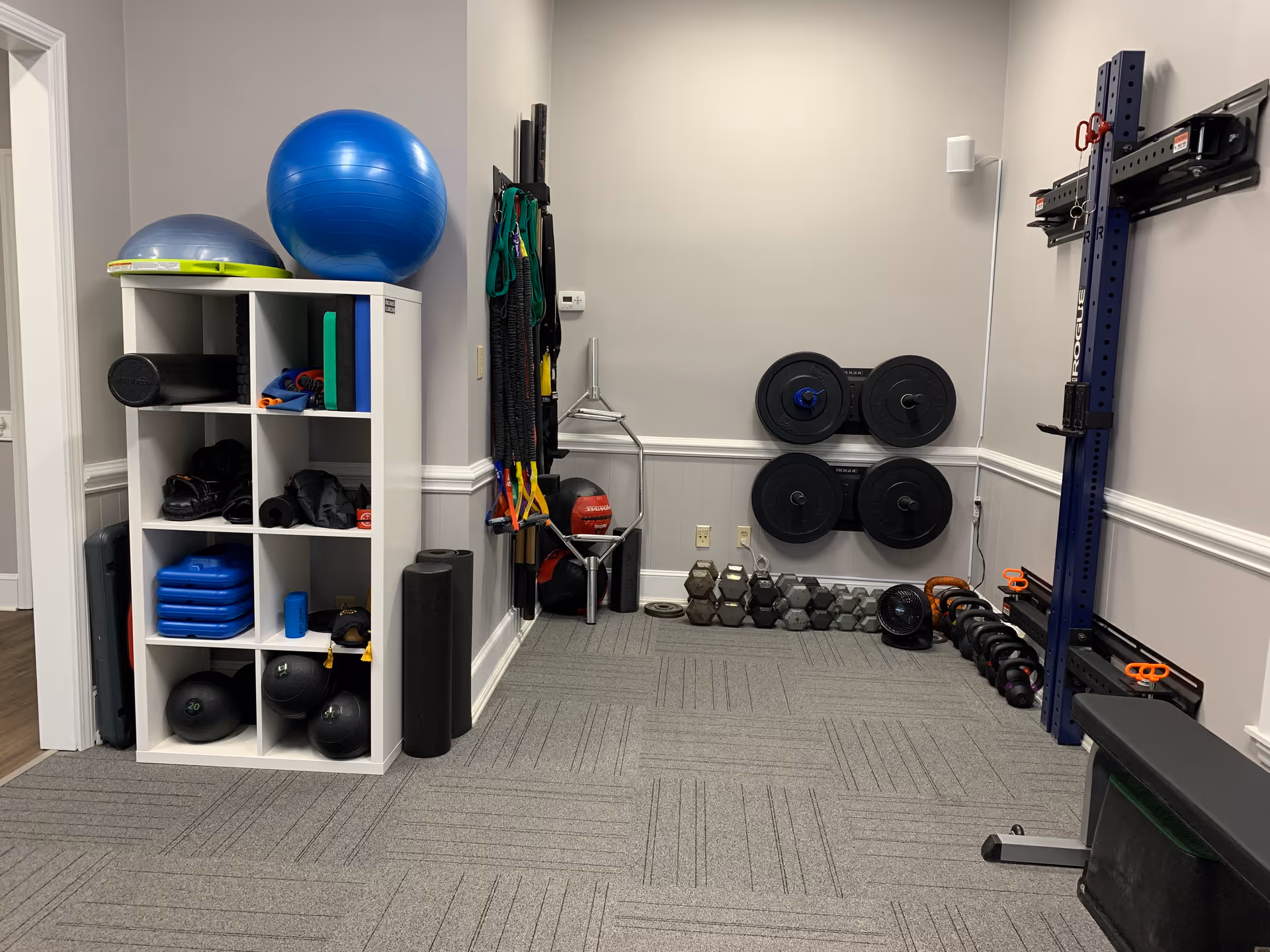 Interior rehab gym with weights, exercise balls, bands, and organized storage.