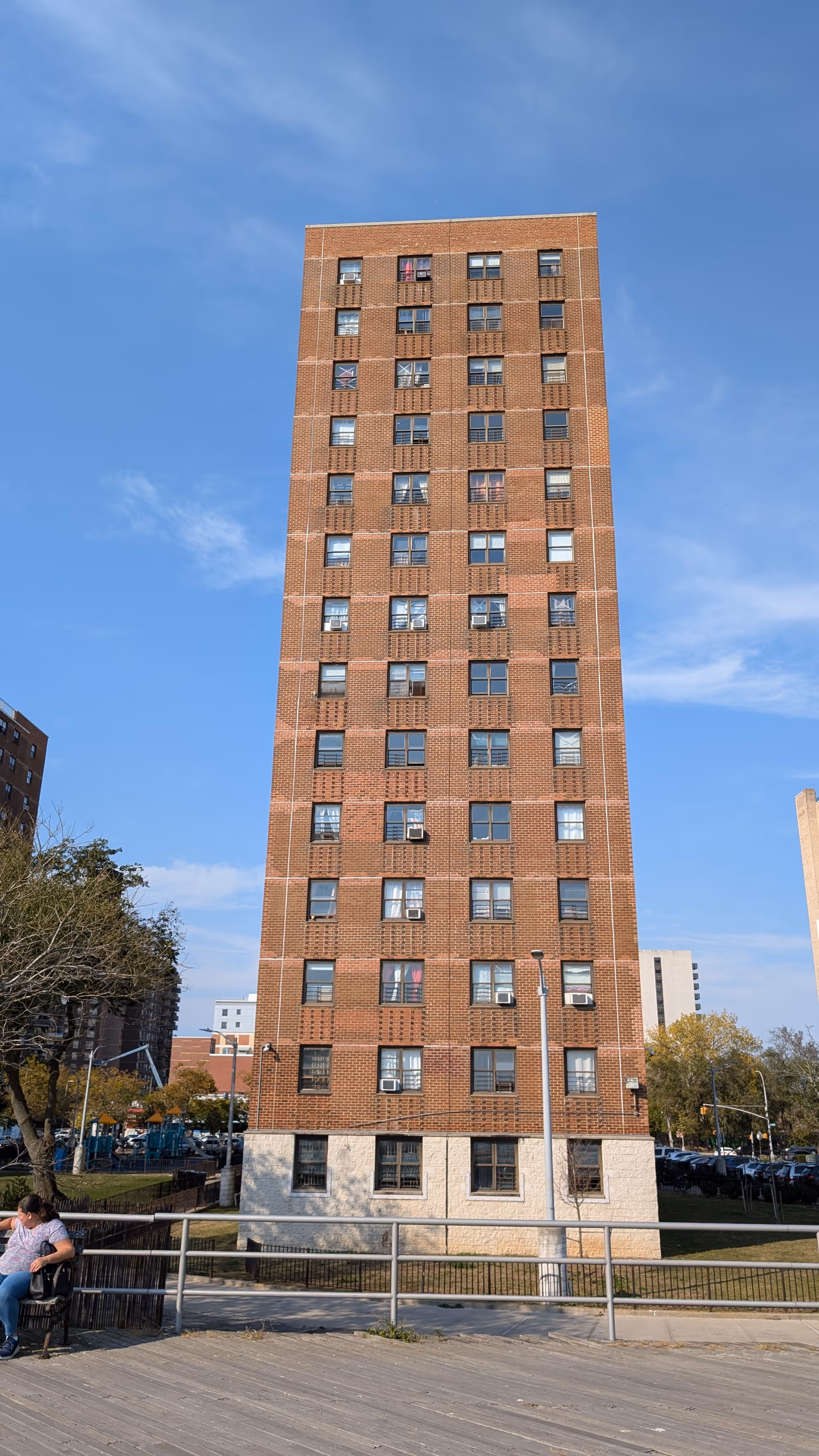 Tall brick apartment building with many windows under blue sky