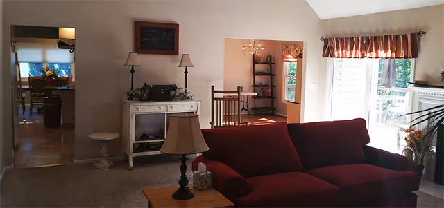 Cozy living room with red sofa, lamps, and doorway to another seating area.