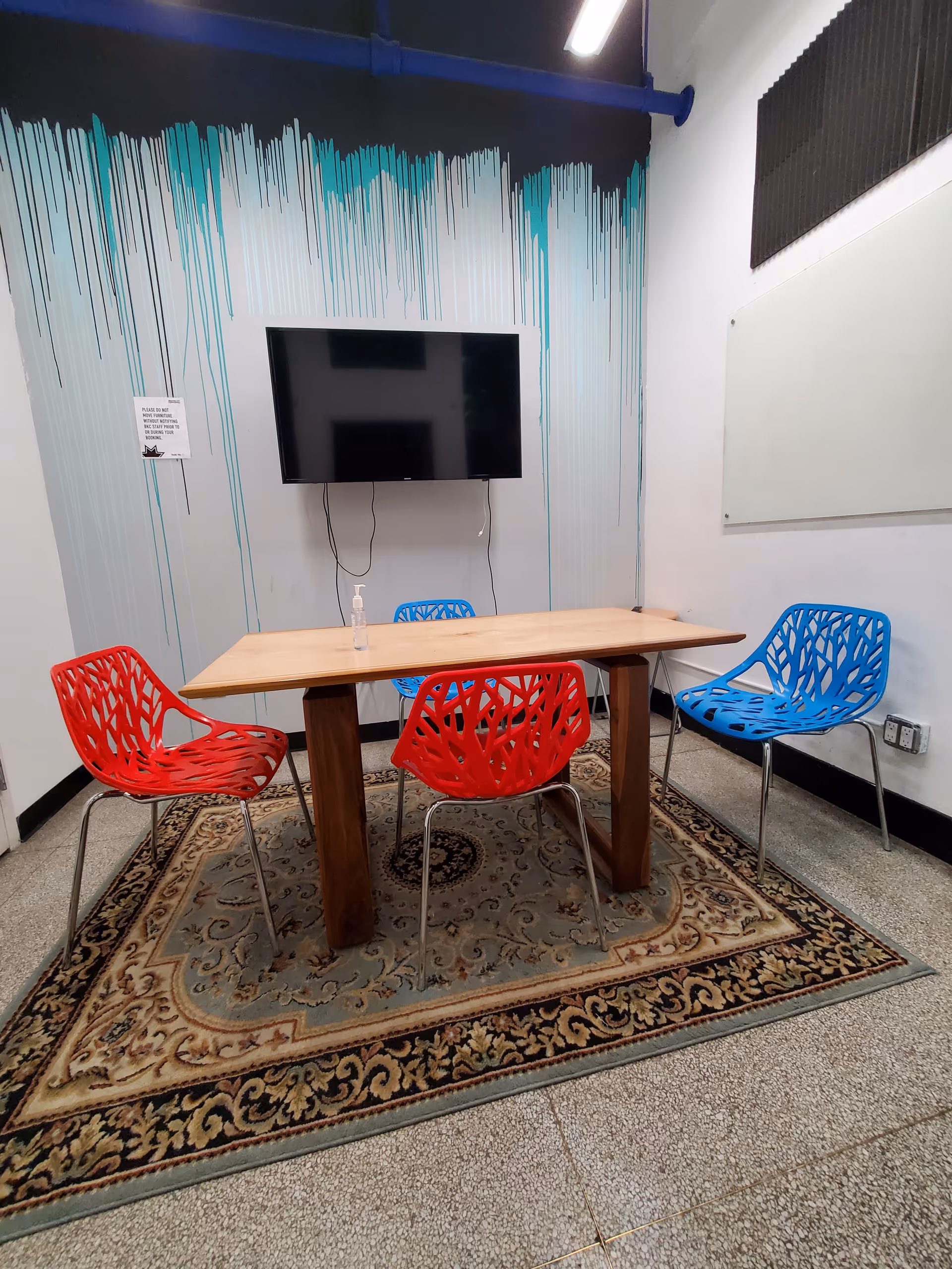 Colorful plastic chairs surround a wooden table in a small interior dining area.