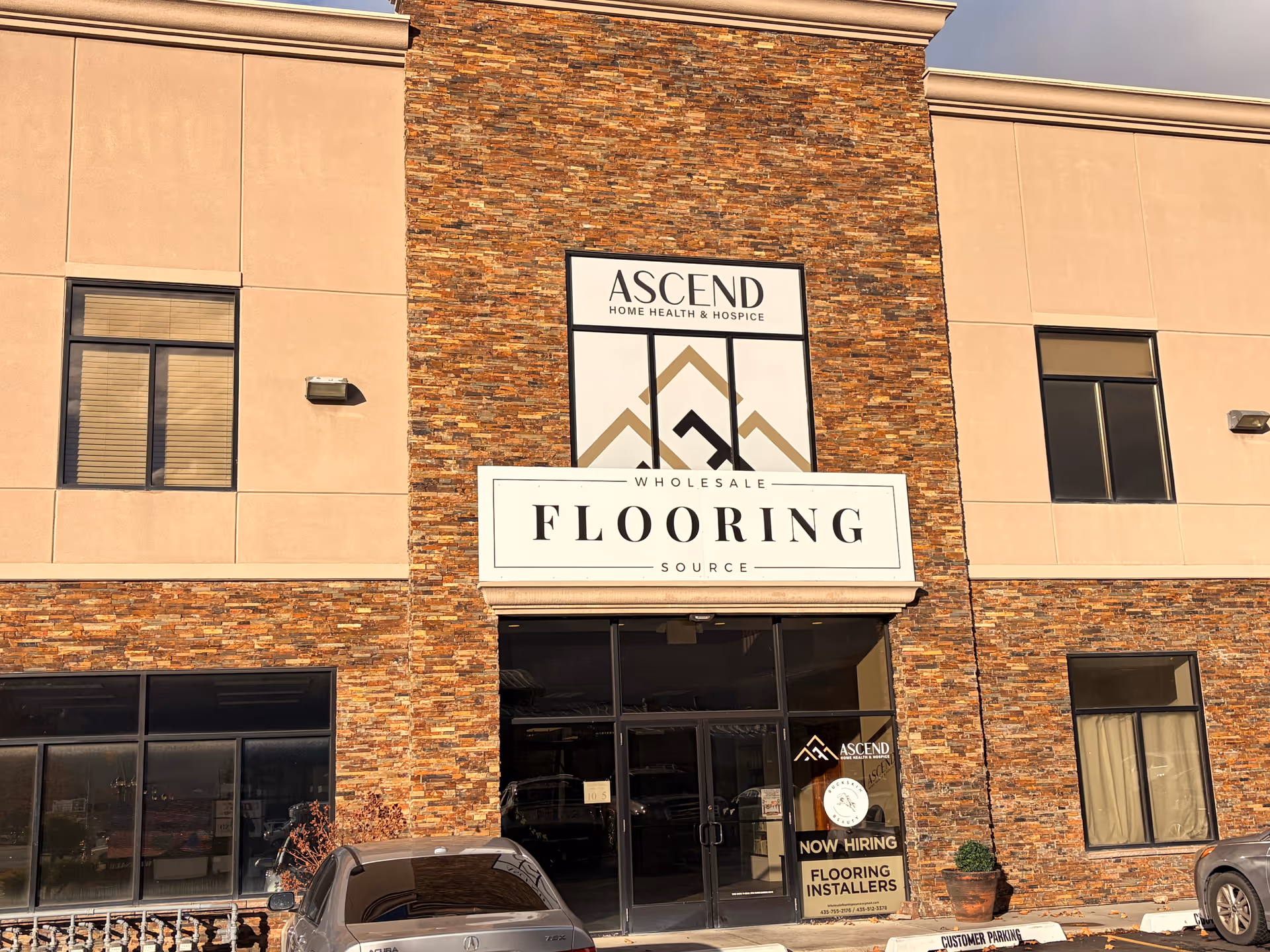 Brick storefront with Ascend Home Health & Hospice sign above a flooring store.