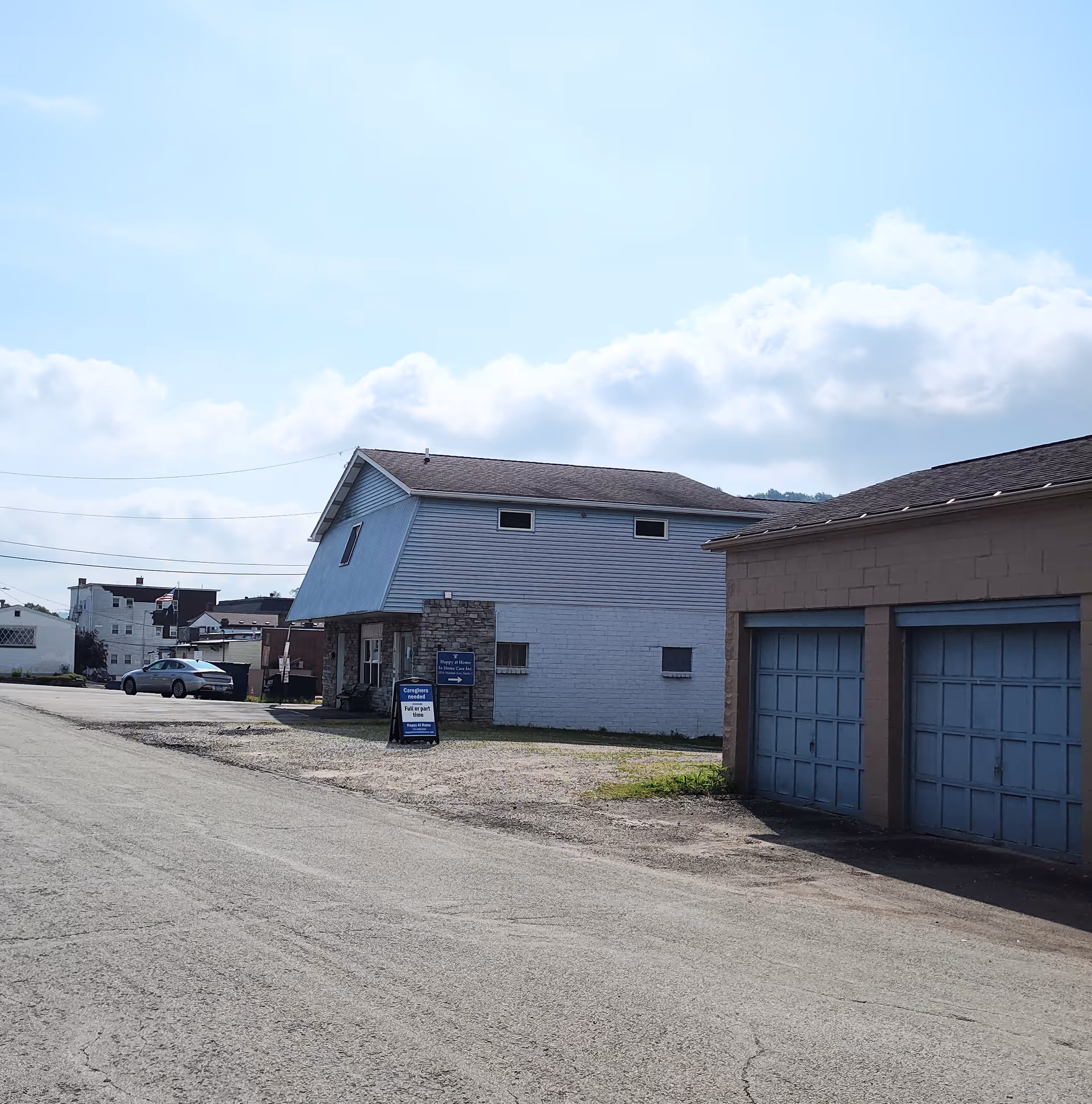 Exterior view of a small care facility with a signboard and attached garages.