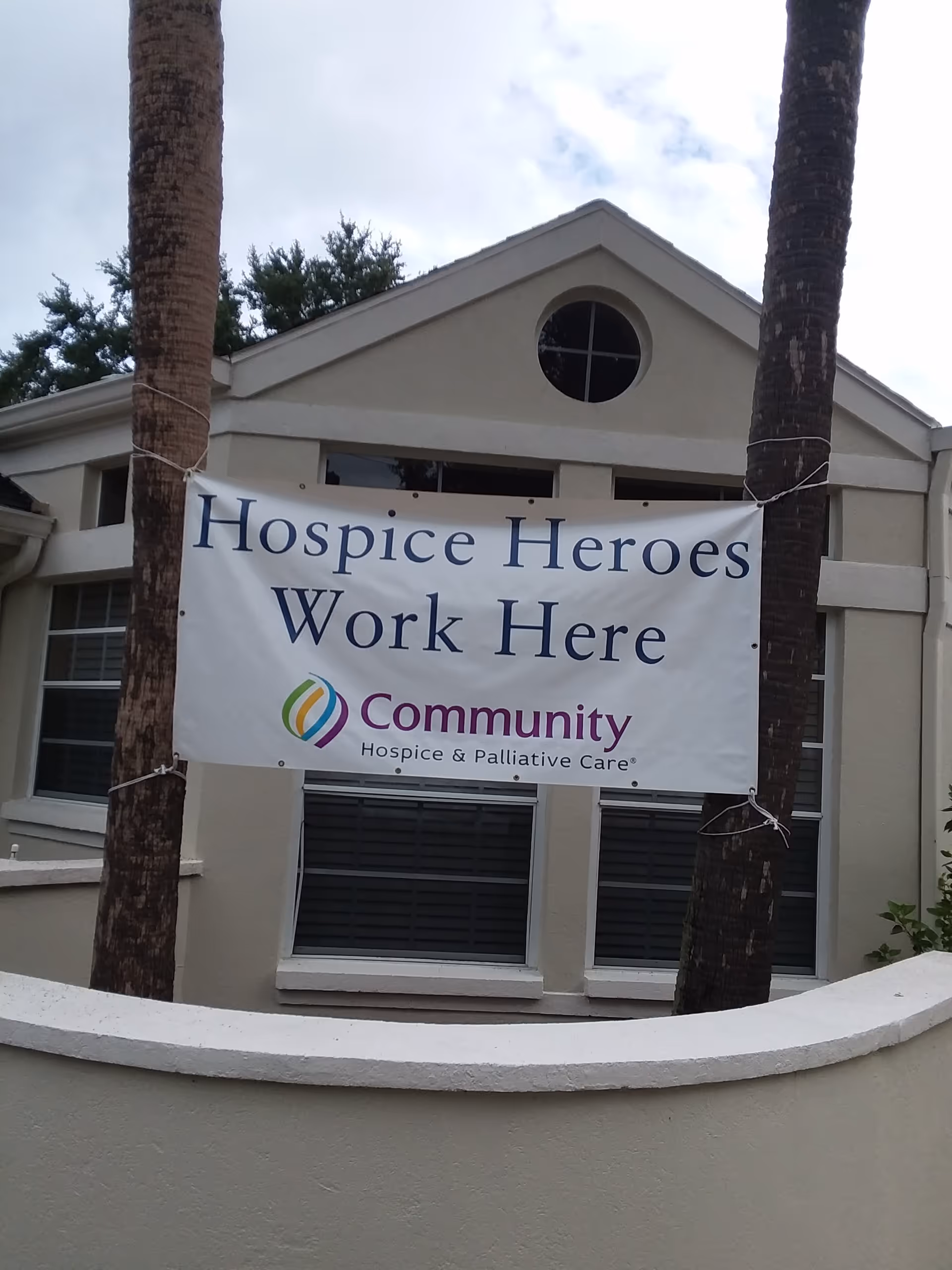 Front view of a beige building with a banner reading Hospice Heroes Work Here.