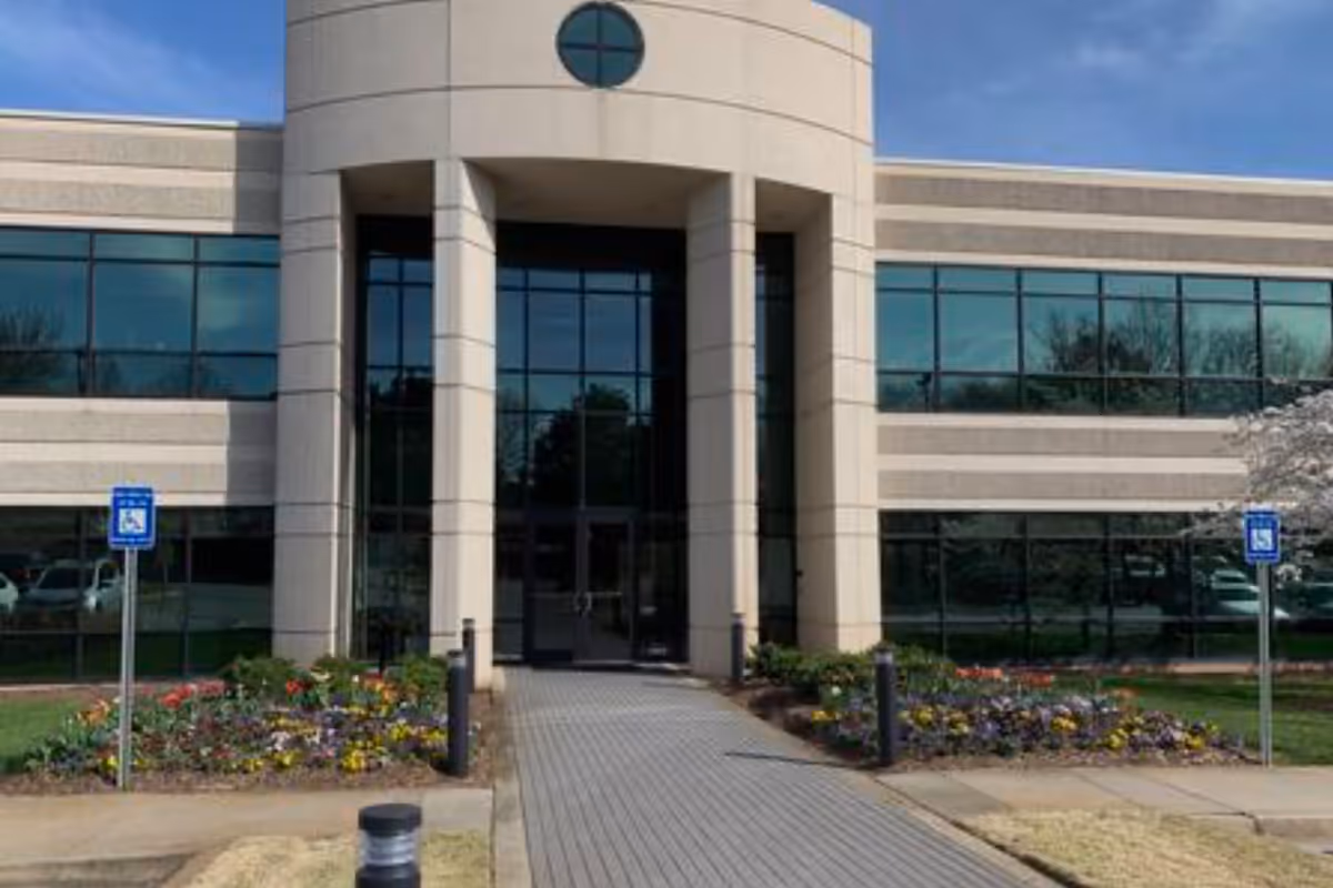 Modern senior living facility entrance with glass doors and landscaped walkway.