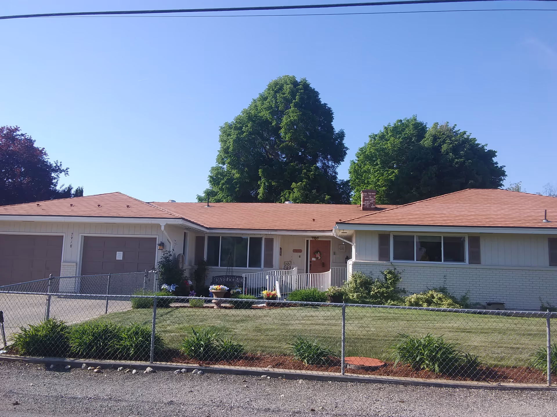 Allen's Adult Family Home II exterior: single-story with red roof, front lawn, and chain-link fence.