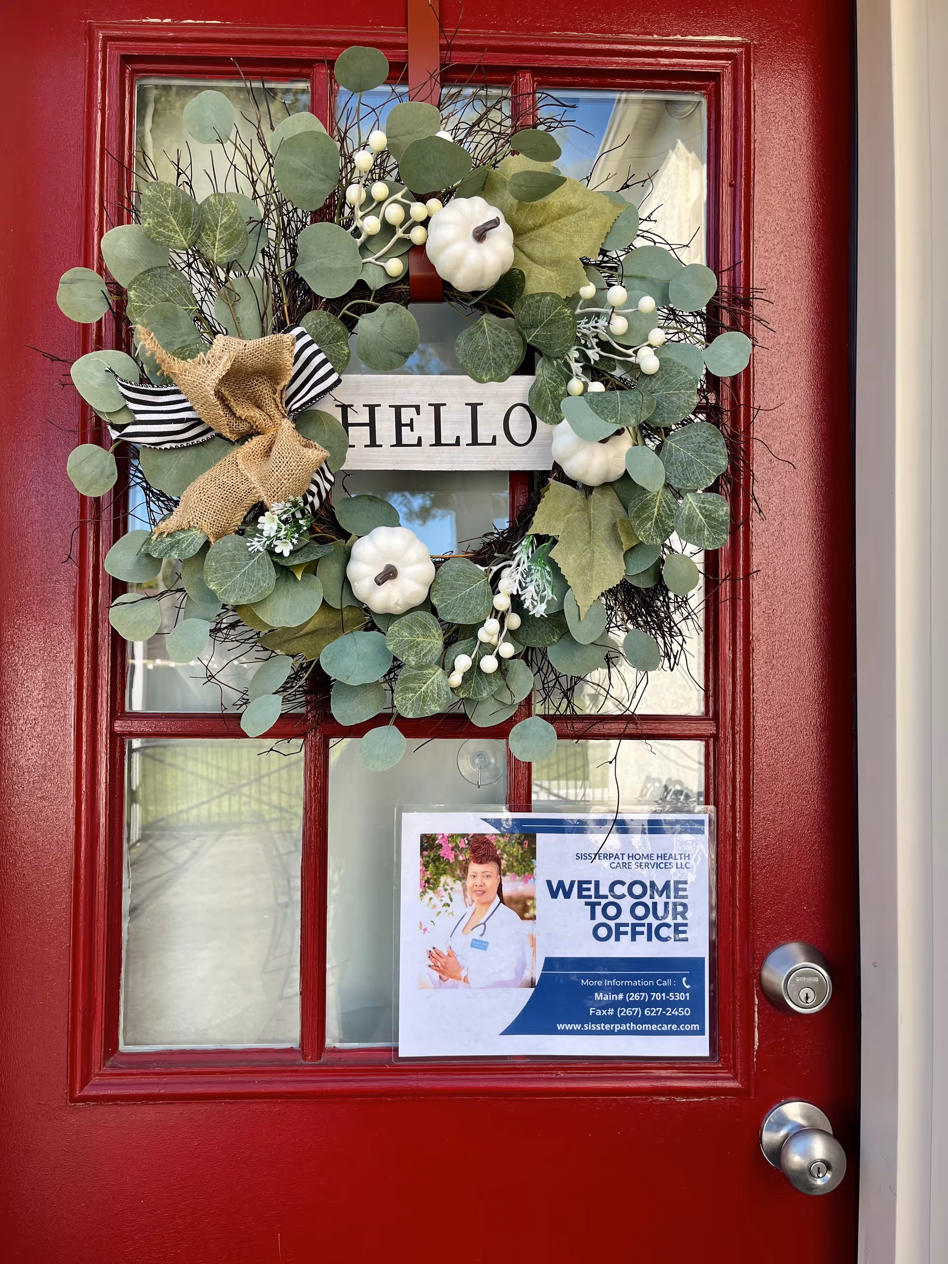 Red front door with wreath and hello sign for Sissterpat Home Health Care Services LLC.
