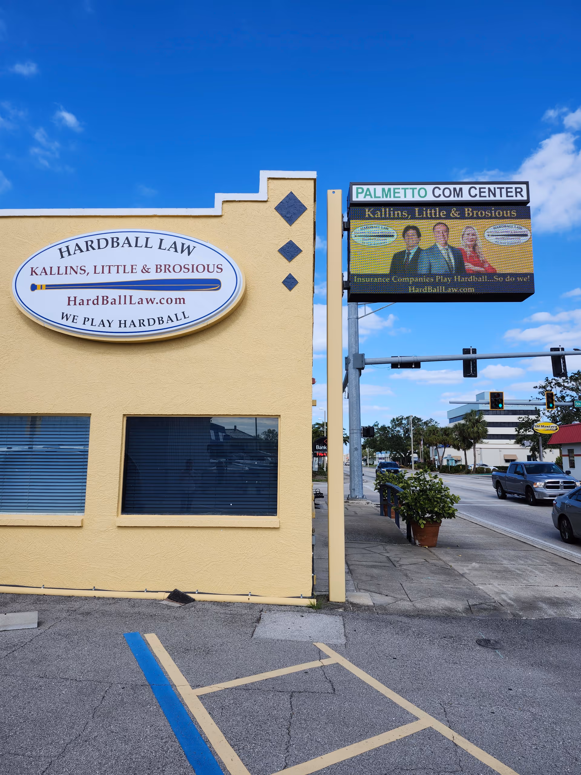 Yellow building facade with a large Hard Ball Law sign and a Palmetto Com Center sign