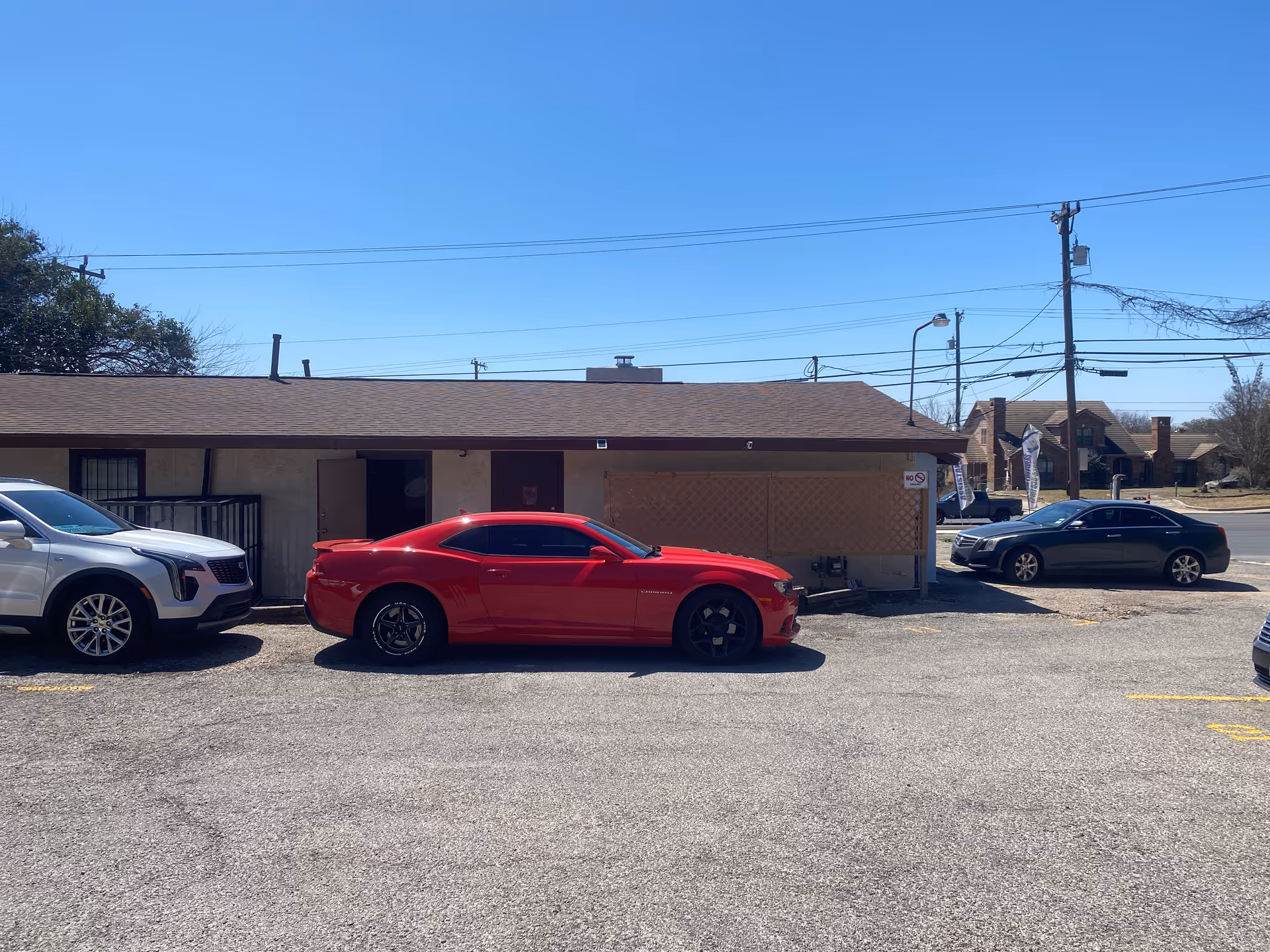 Single-story building exterior with a parking lot and several cars in front.