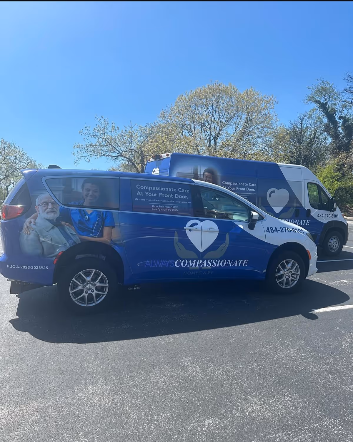 Blue branded vans parked in a lot with a heart logo and Compassionate branding.