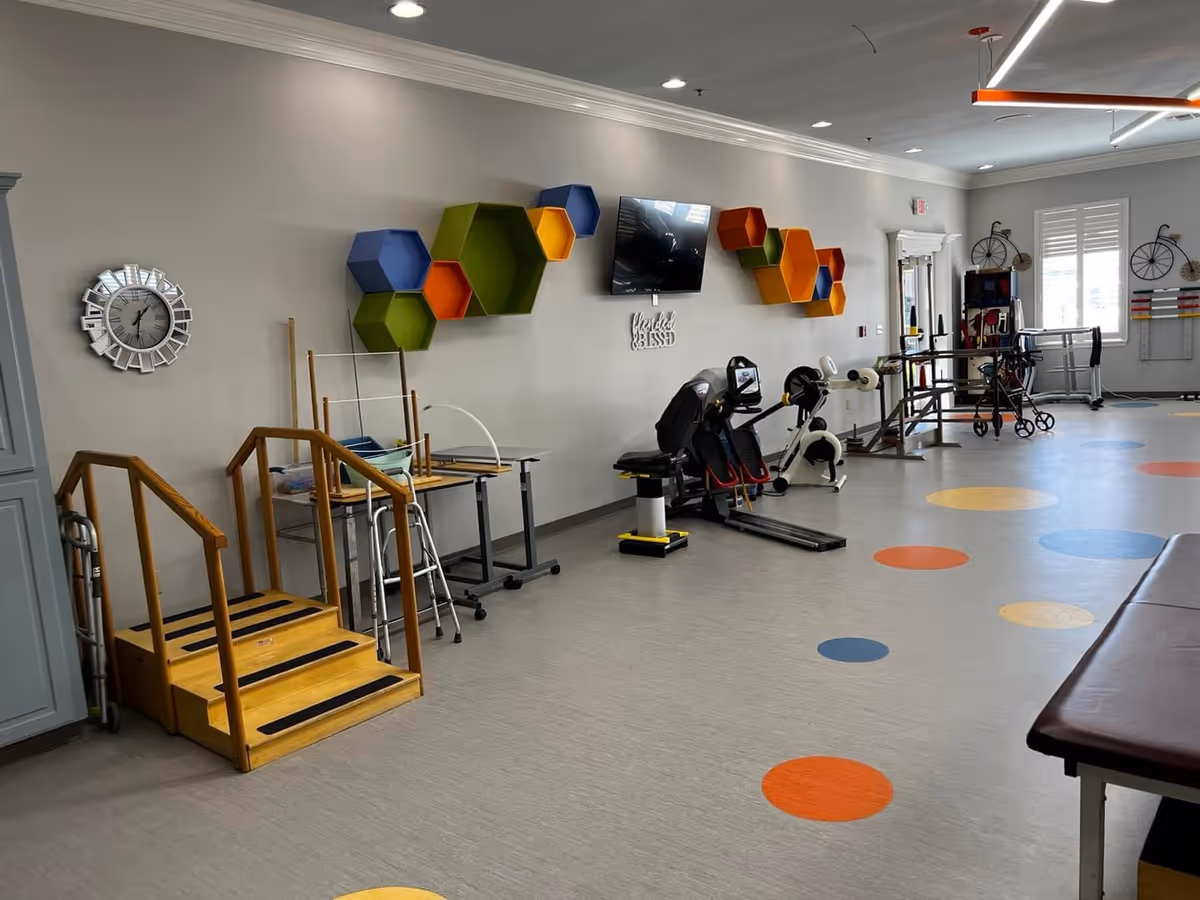 Rehabilitation therapy room with exercise equipment, parallel bars, practice stairs, and colorful wall shelves.