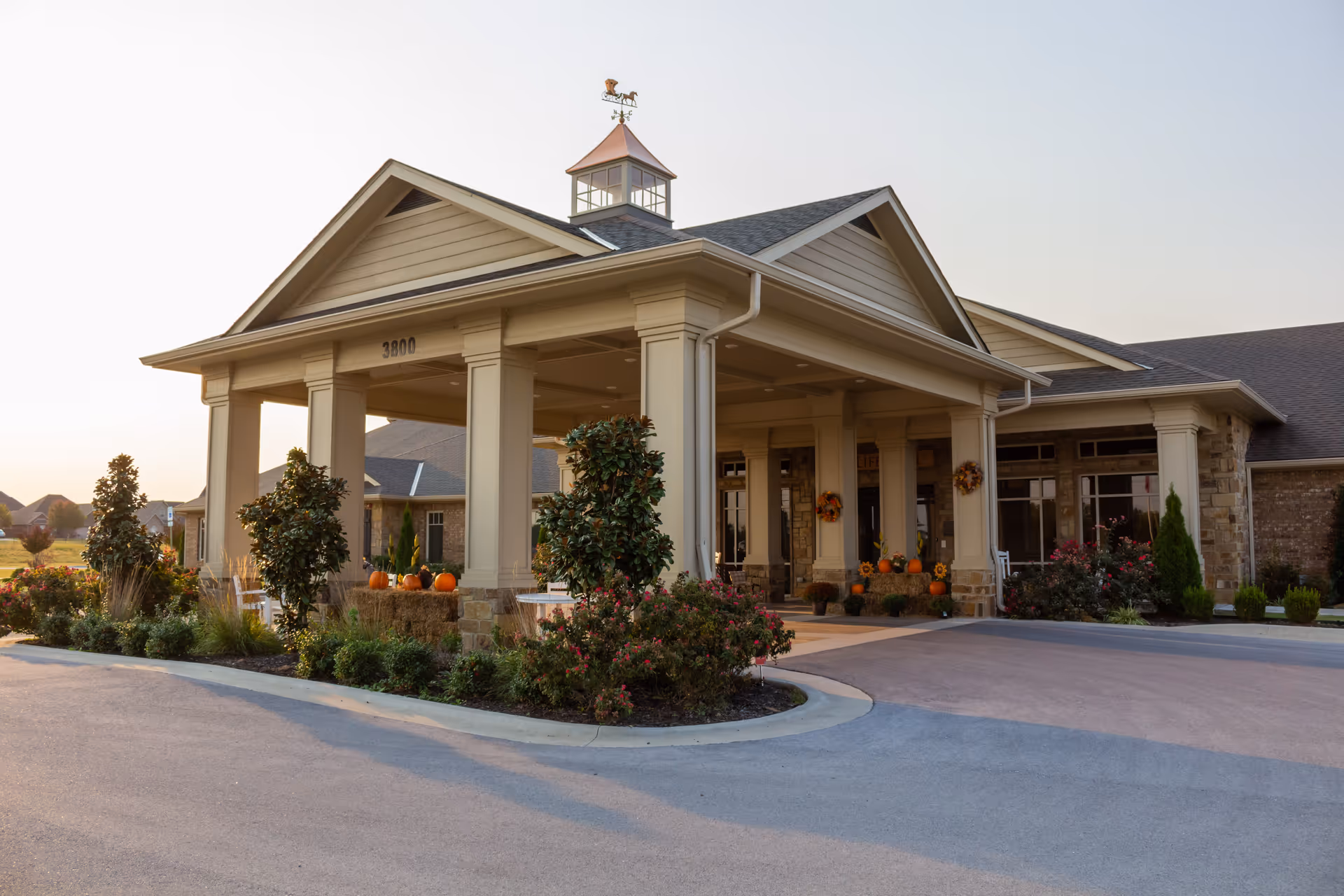 Front entrance of Village on the Park Bentonville with pumpkins and landscaping.