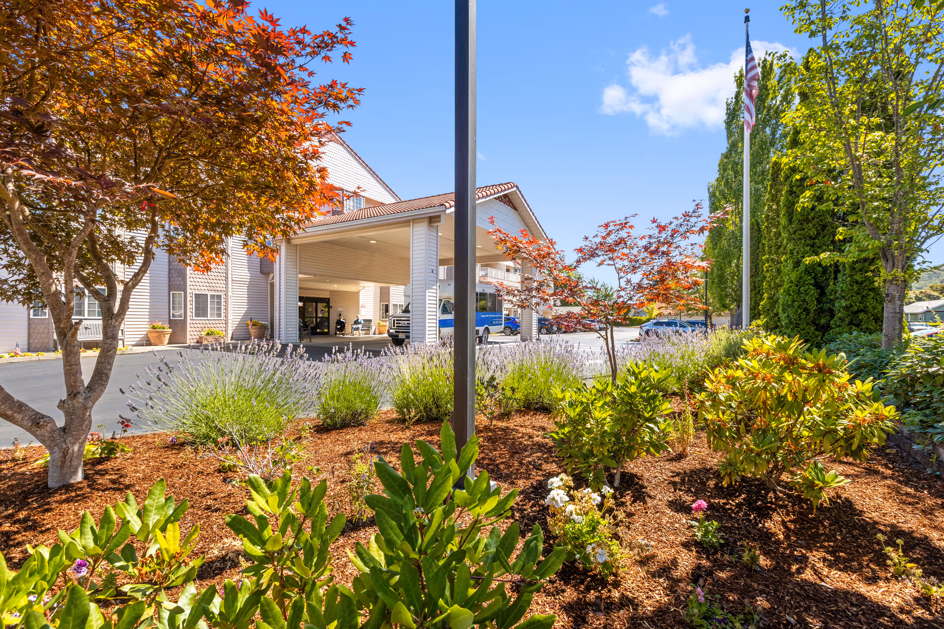Front exterior of Riverview Terrace with landscaped bushes, trees, and a flagpole.