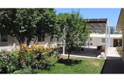 Outdoor courtyard of a care facility with trees, flower beds, and a covered walkway.