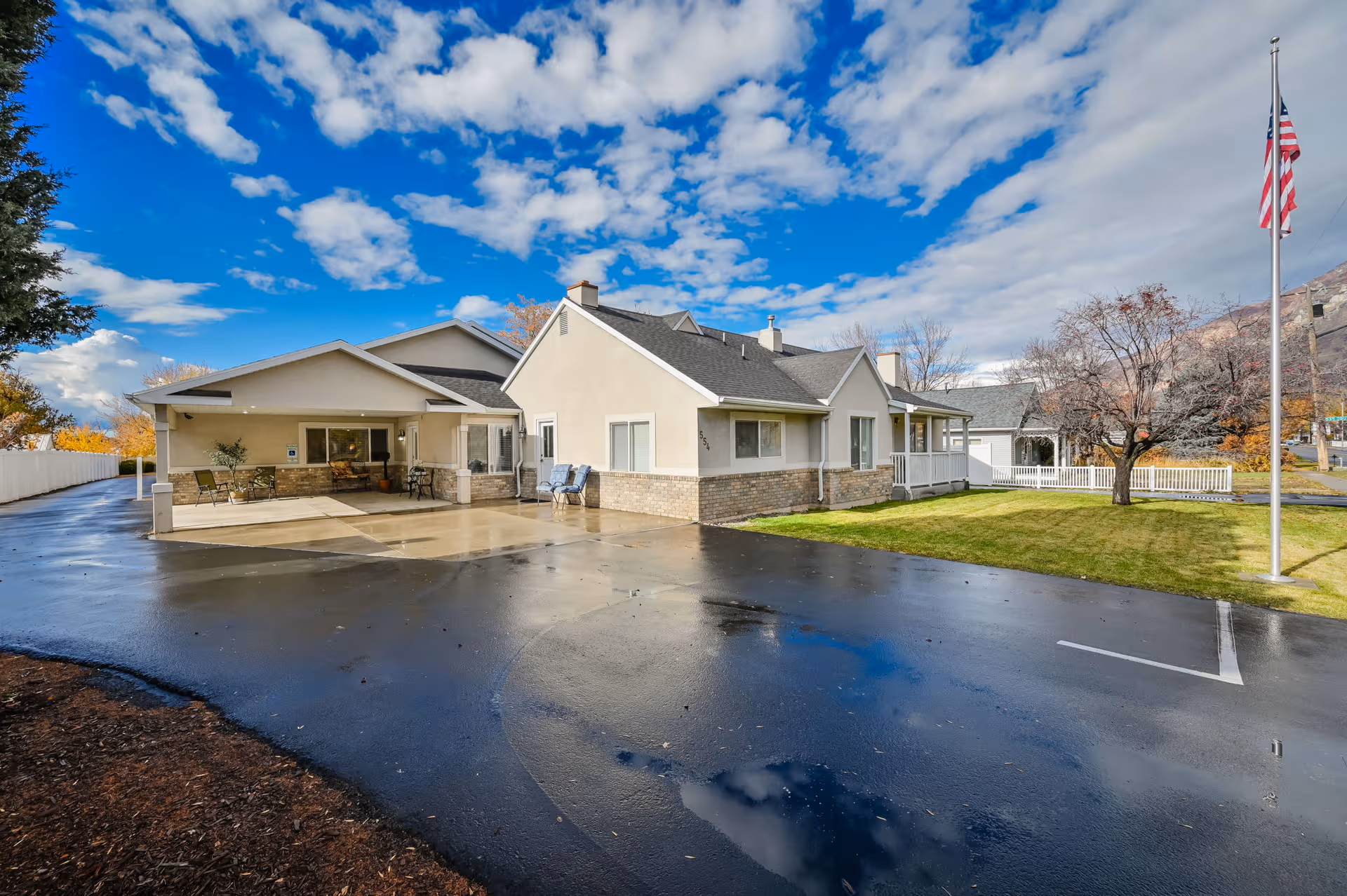 Exterior view of Canterbury Assisted Living WEST facility with driveway, lawn, and flag.