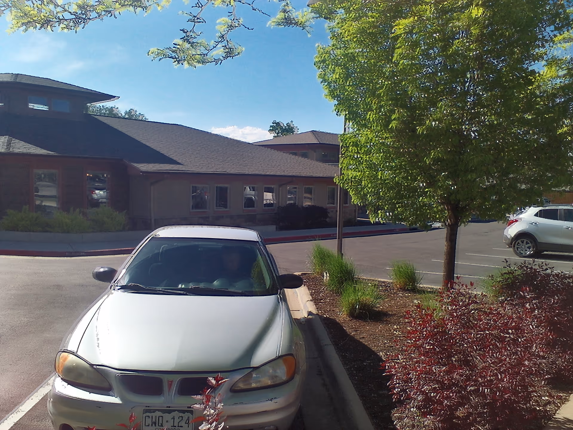 Exterior view of a rehabilitation center with a parking lot and trees in front.