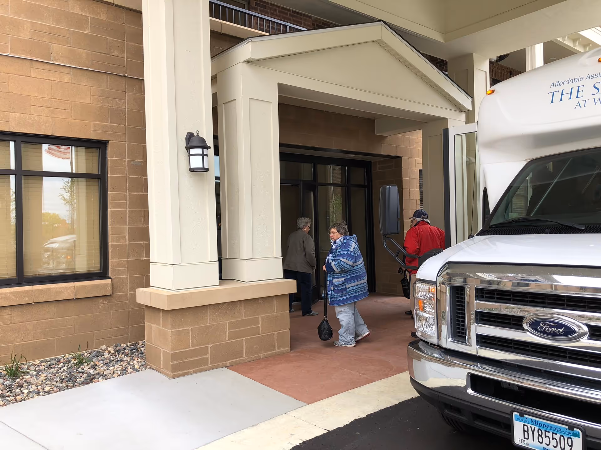 Residents enter Choice Connections facility through a covered entrance beside a parked van.