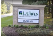 Exterior sign for The Laurels of University Park with landscaping.