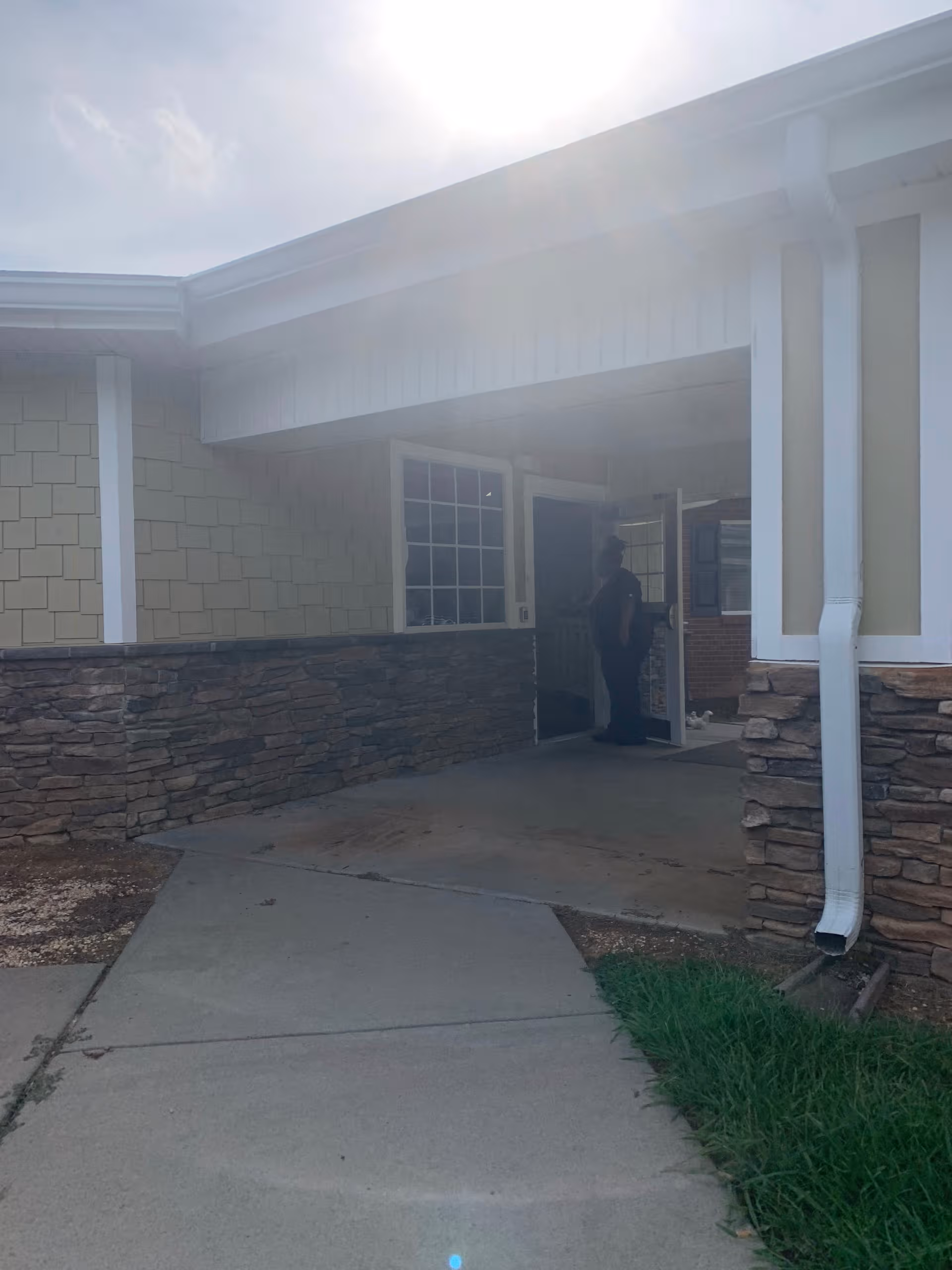 Front entrance of a senior living facility with stone lower walls and a person nearby.