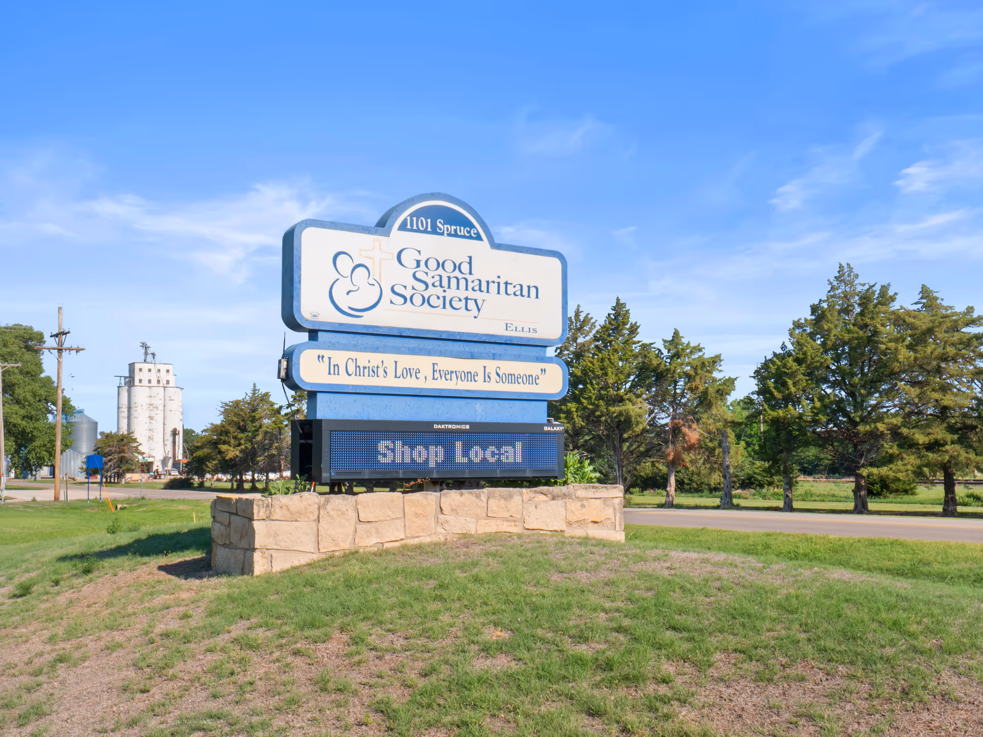 Outdoor sign for Good Samaritan Society Ellis on a stone base under blue sky.