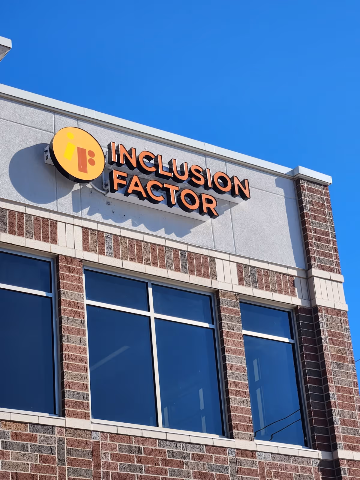 Exterior view of a brick building with an 'Inclusion Factor' sign.