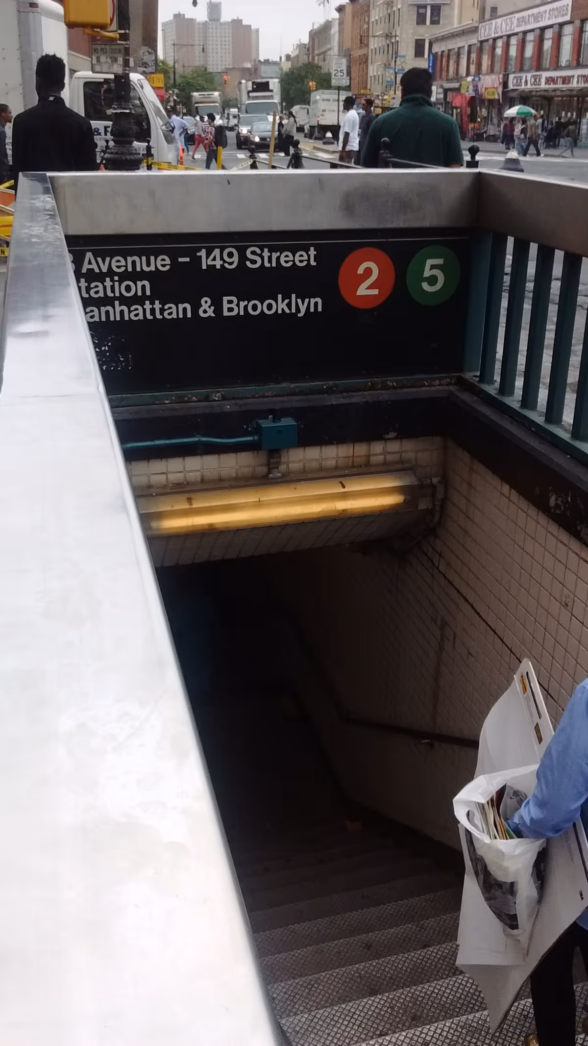Urban subway entrance with stairs descending into a busy city street scene.
