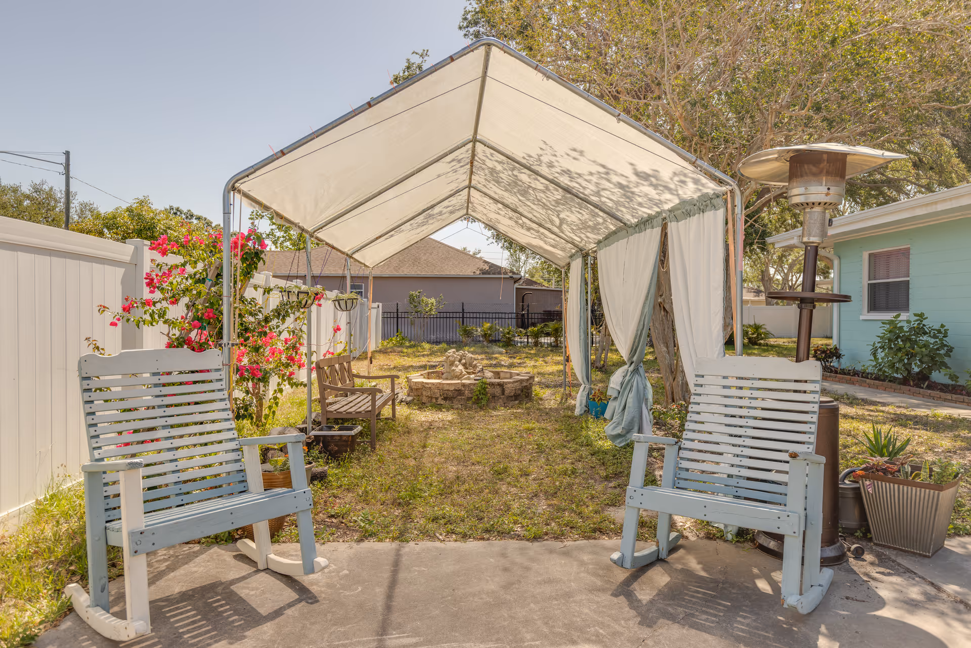 Outdoor patio with a canopy, two rocking chairs, and a central fire pit.