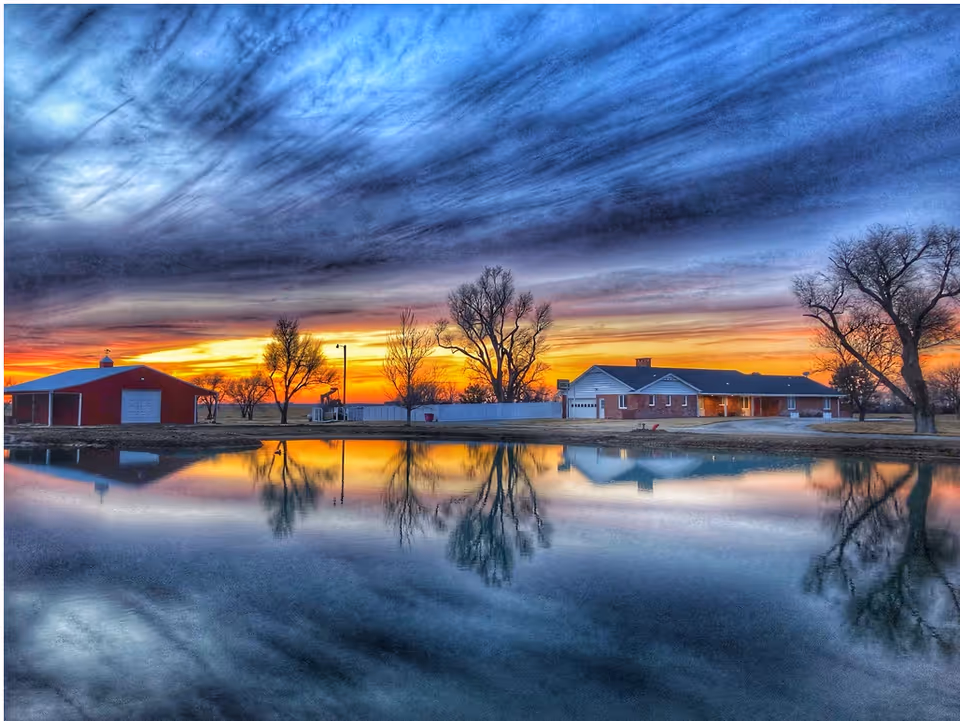 Sunset over a senior living campus with a brick building beside a calm lake.