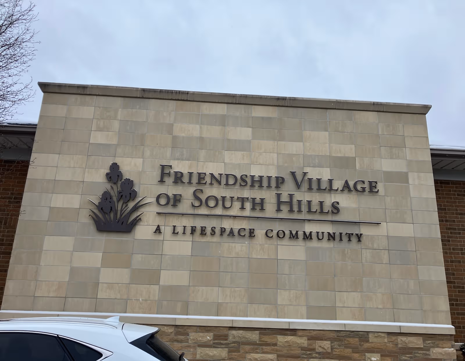 Exterior wall of Friendship Village of South Hills with a large sign.