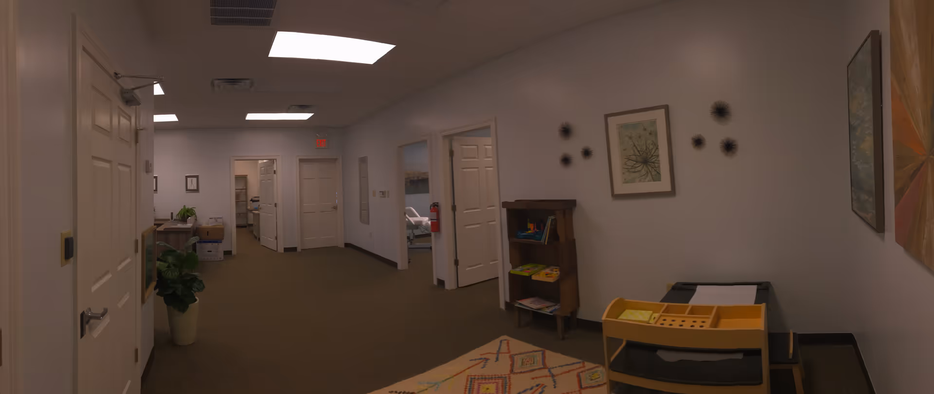 Interior hallway of a senior living facility with doors, furniture, and wall art.