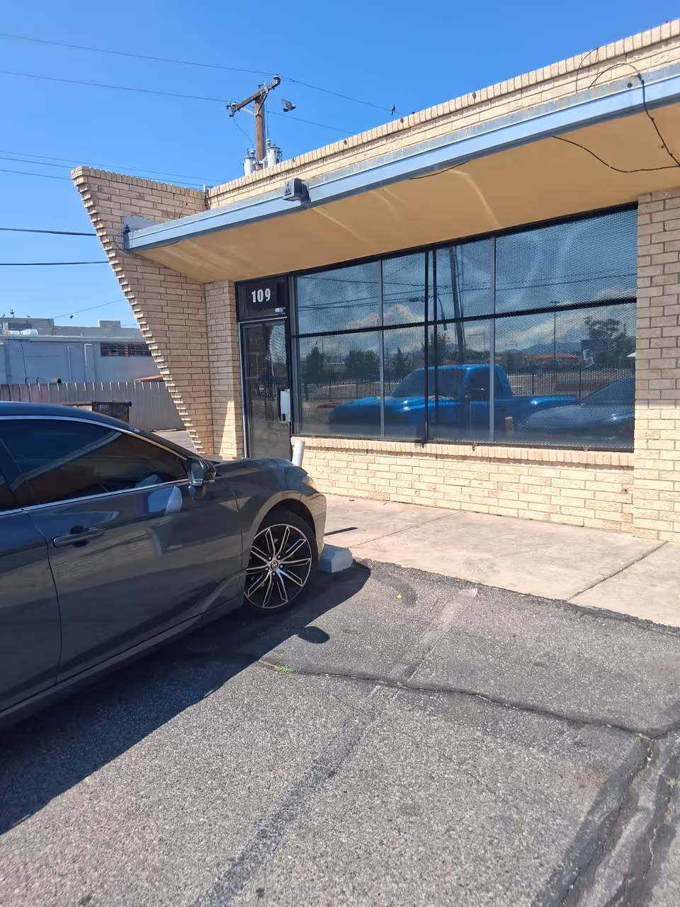 Brick senior care facility front with large glass windows and a parked gray car.