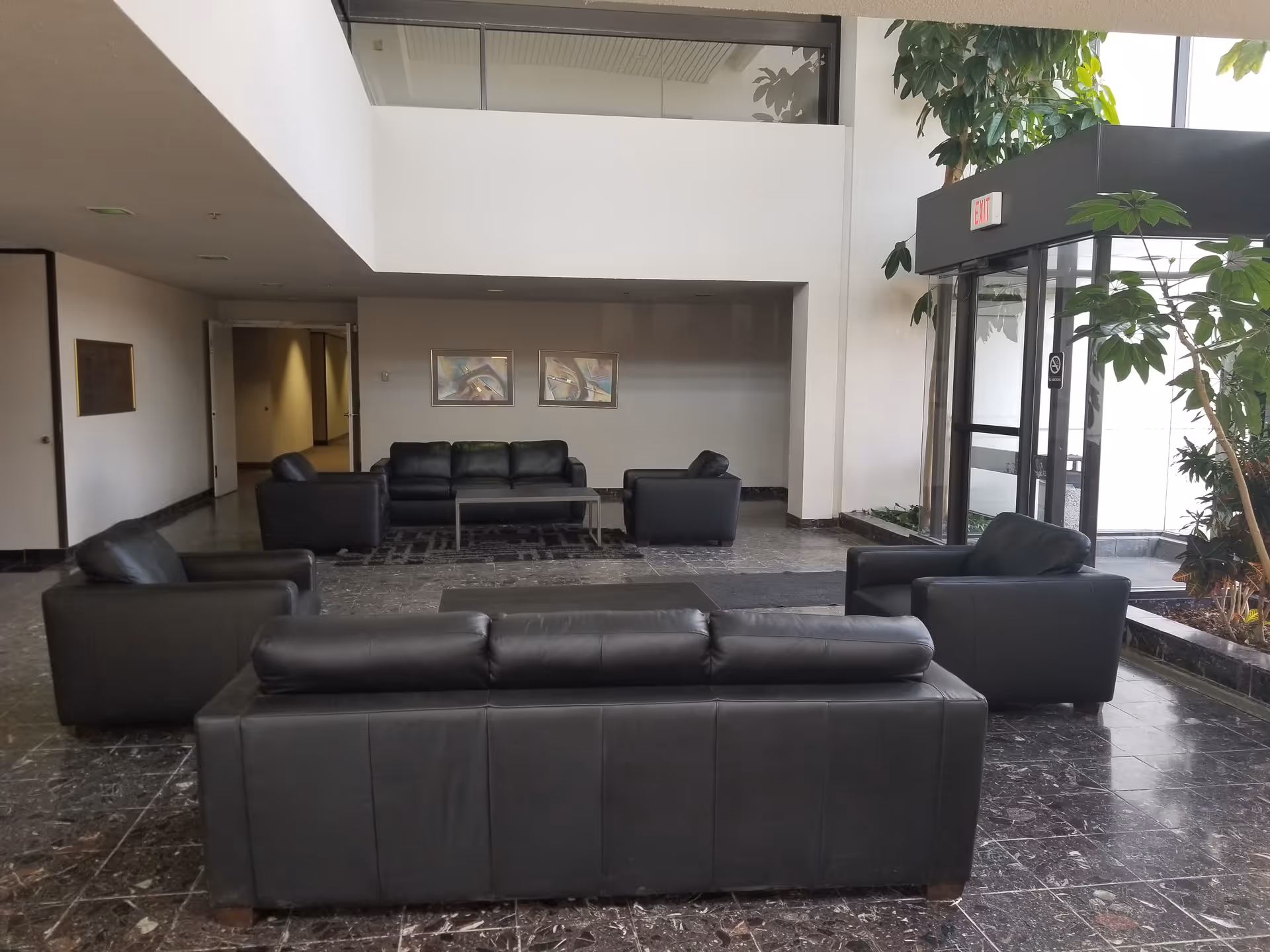 Lobby area of a senior care facility with black leather couches and glass entrance.