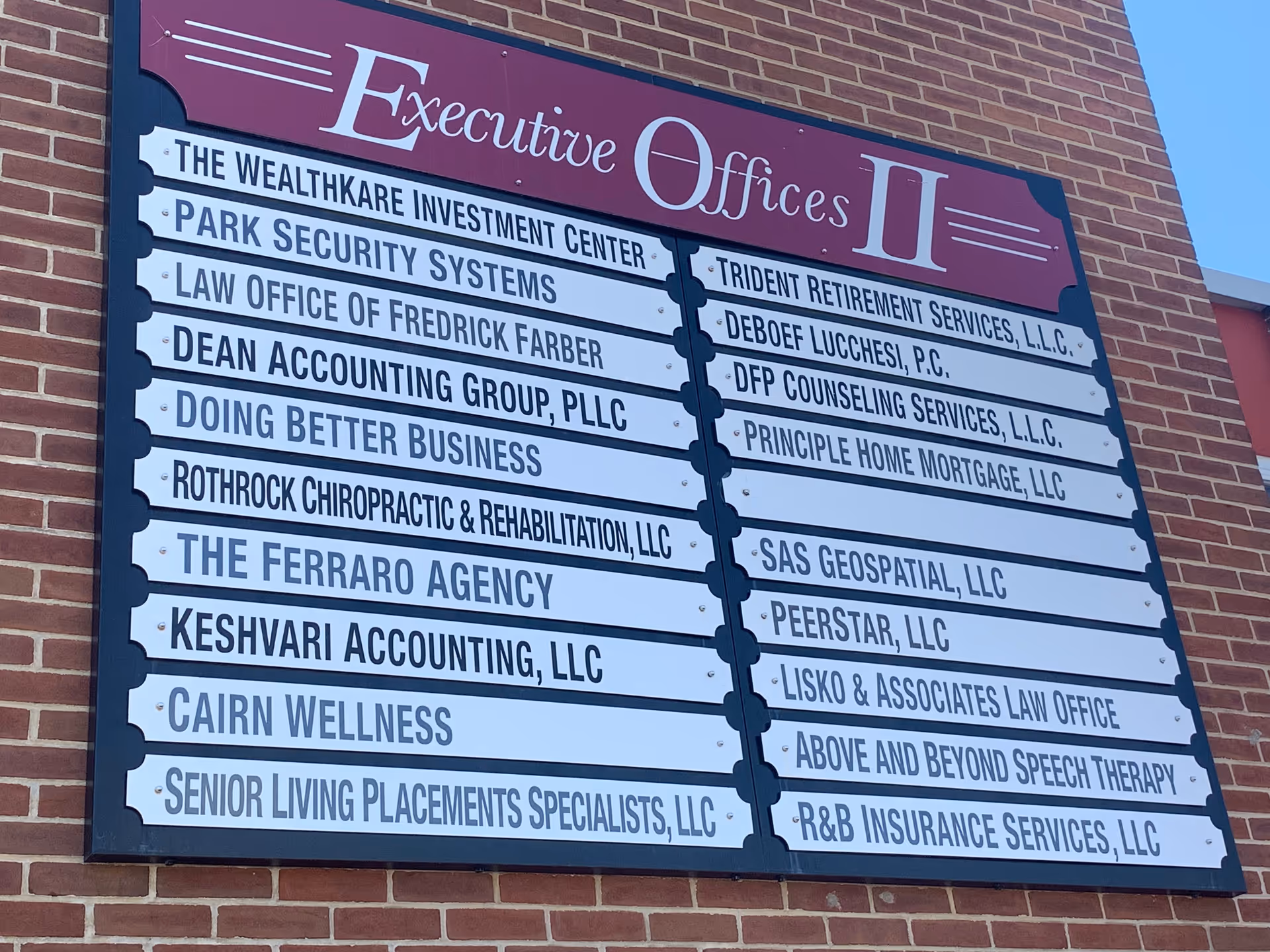 Brick building with a large signboard listing multiple company names under Executive Offices II.