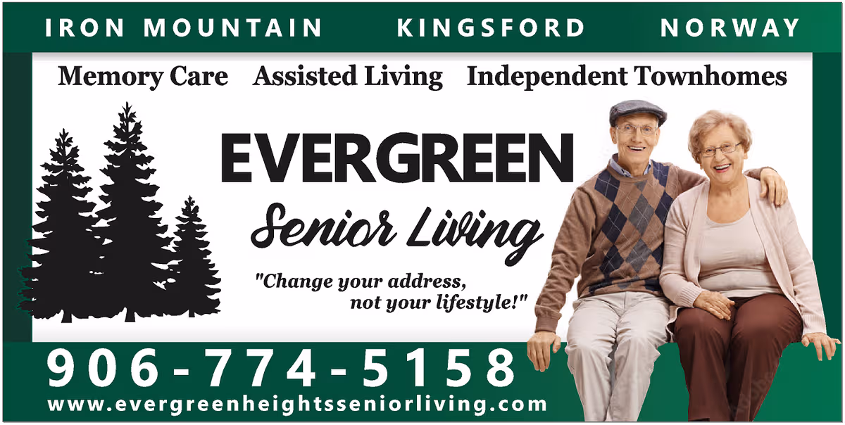 A large Evergreen Senior Living sign on a building front with two elderly people sitting.