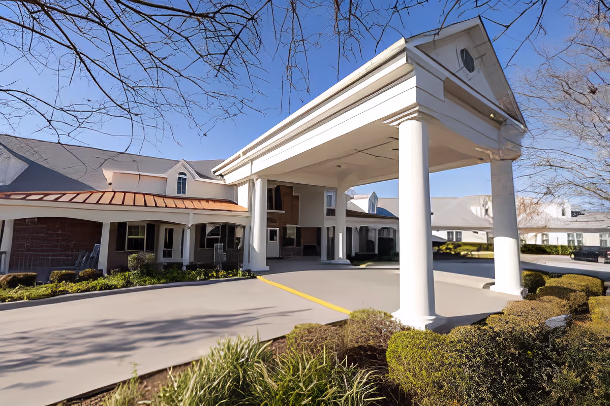 Front entrance of a senior living building with a covered porte-cochère supported by white columns.
