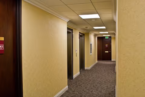 Interior hallway of Care Sharing Home Health facility with beige walls and closed doors.