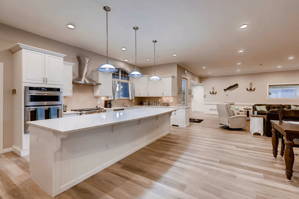 Bright, open kitchen and living space with a large island, white cabinets, and seating.