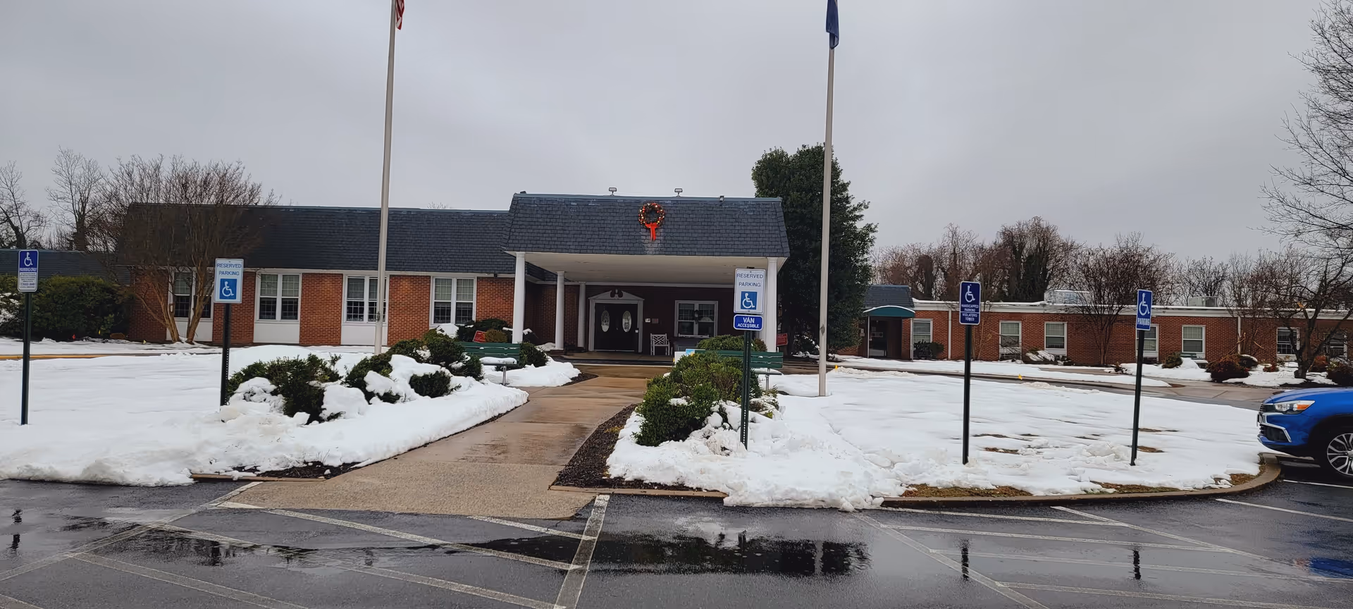 Exterior view of Woodmont Center senior living facility with snow and a covered entrance.