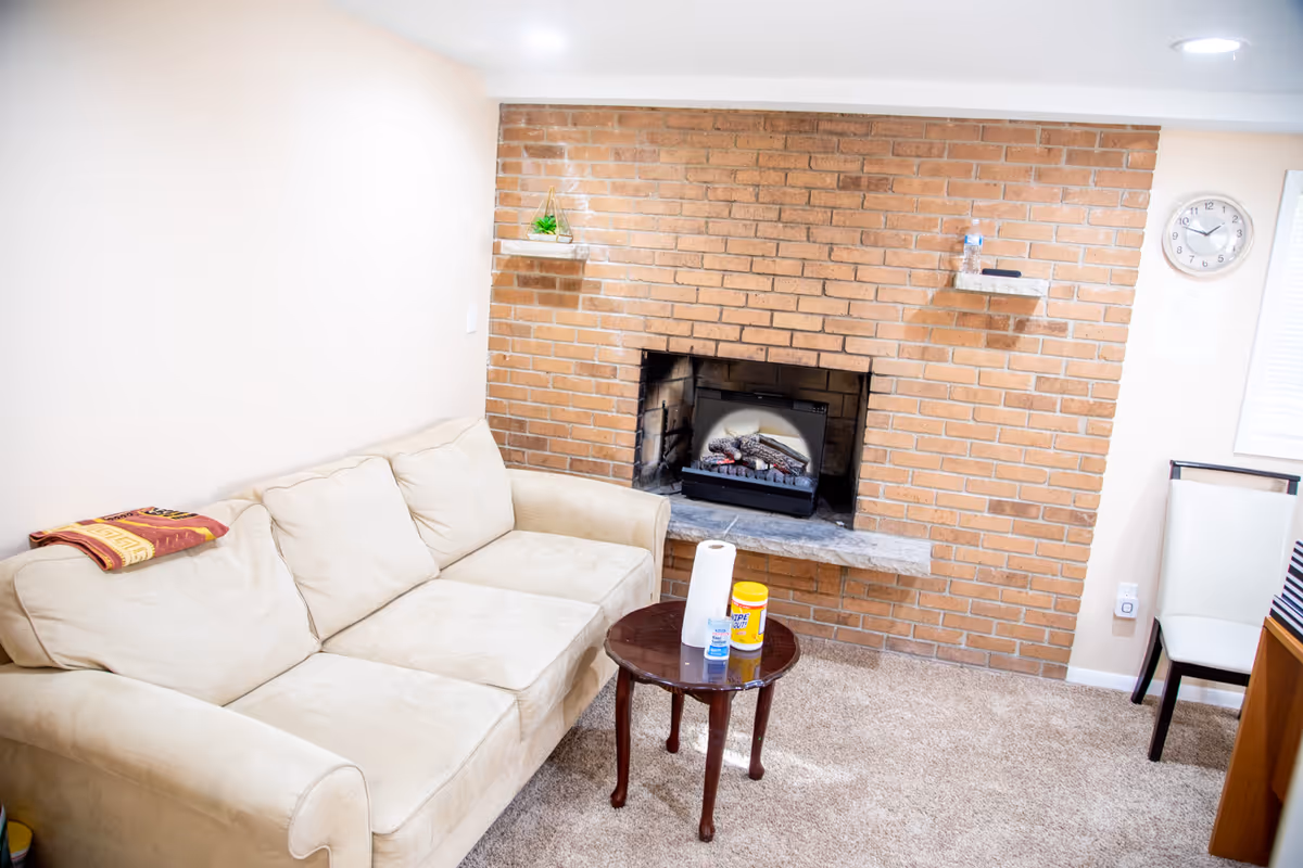 Cozy living room with brick fireplace, beige sofa, and a small coffee table.