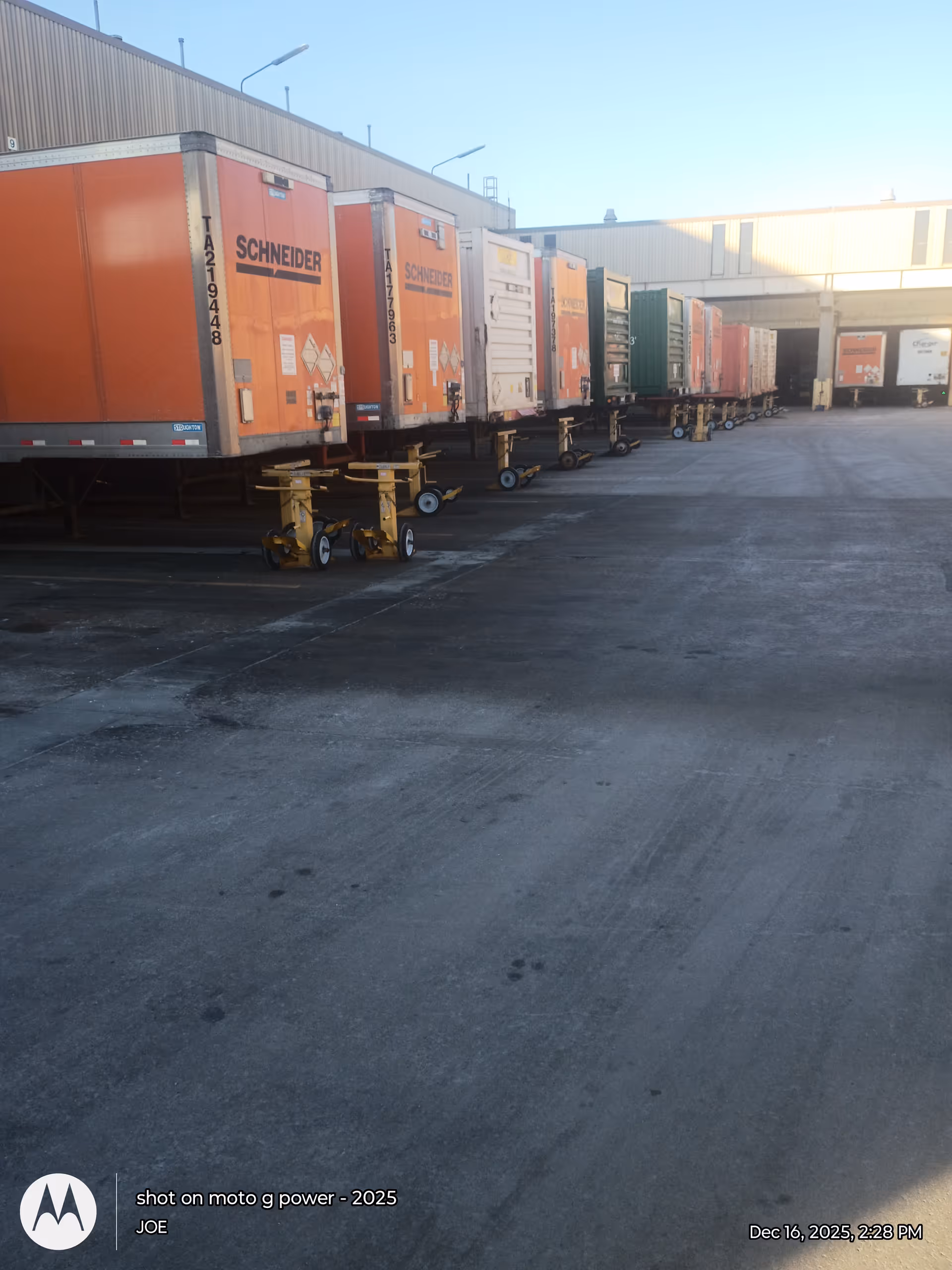 Line of colorful semi-trailers parked at a loading dock beside a building.