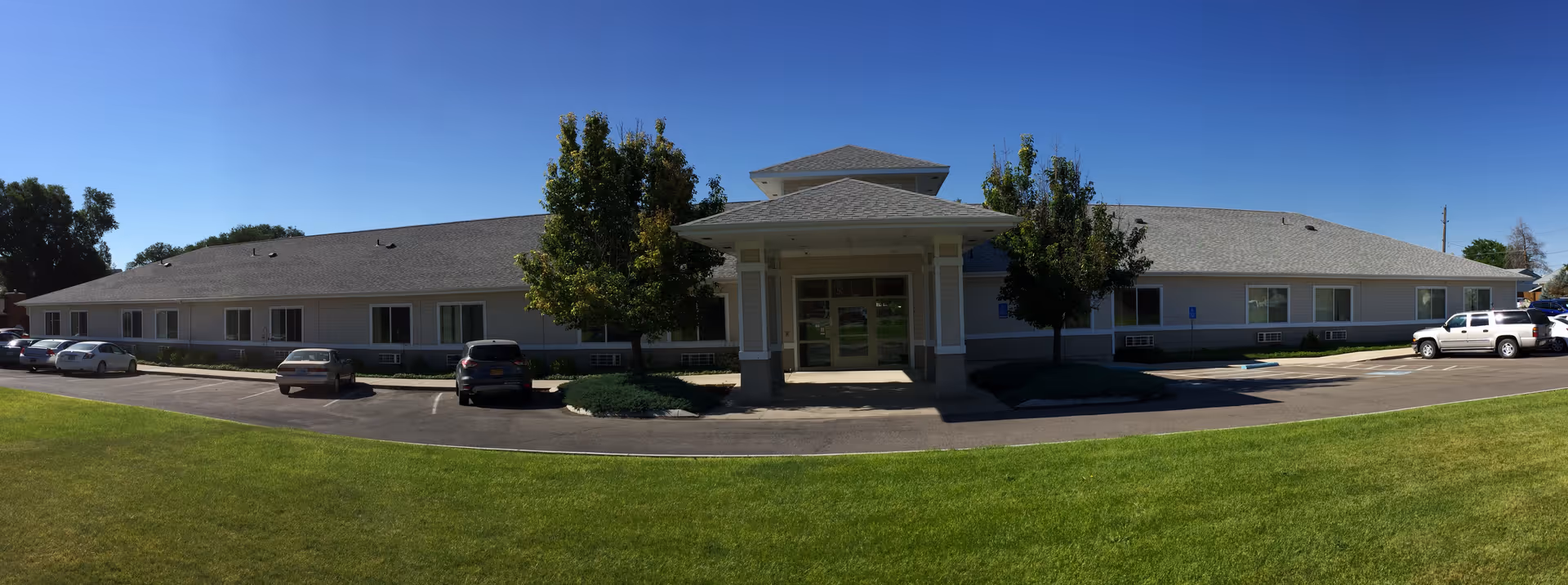 A single-story assisted living facility with a covered entrance and parking in front.