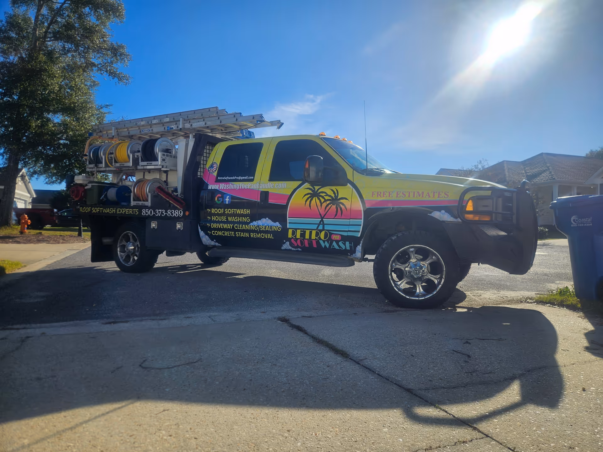 Rainbow-colored service van with hose reels parked on a residential driveway.