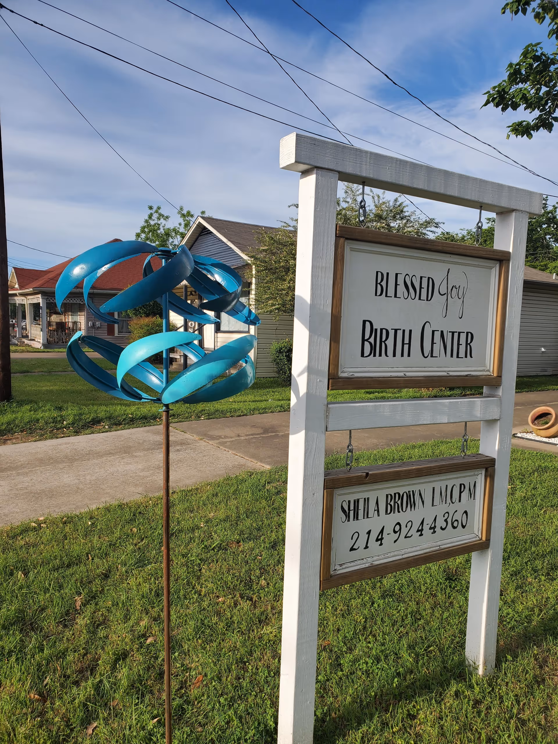 Front yard with a sign reading Blessed Joy Birth Center beside a blue sculpture.