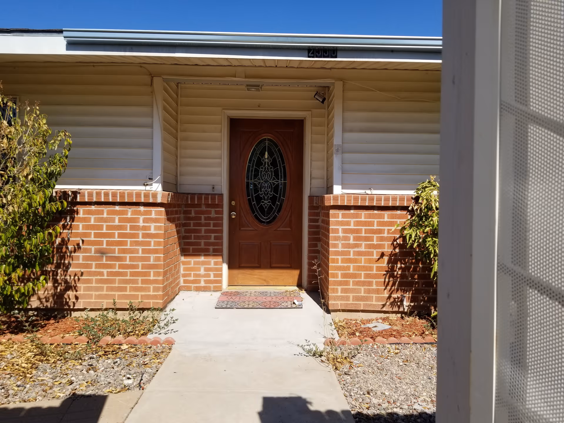 Front entrance of a brick-and-siding building with a wooden door.
